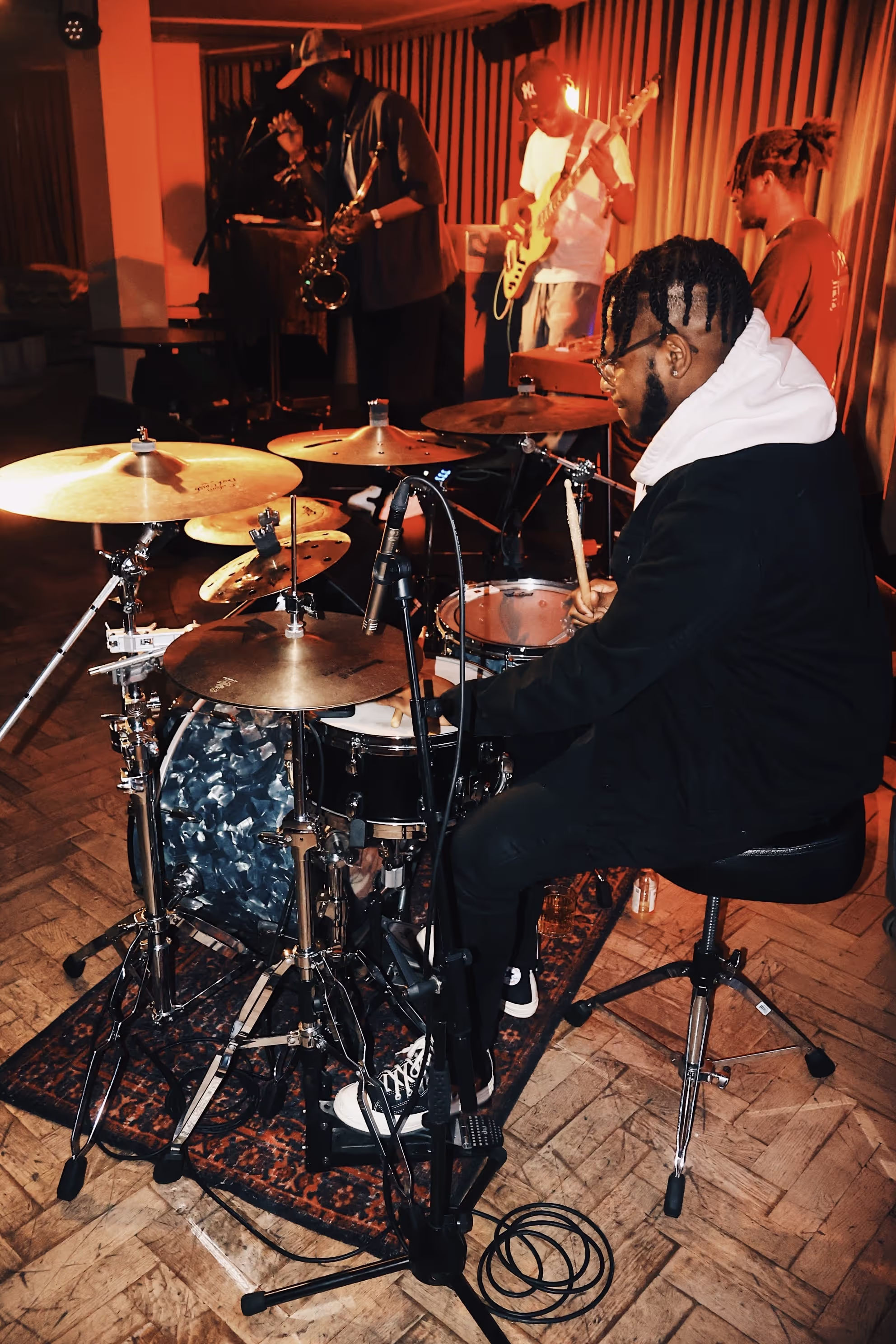 A drummer playing with his band in the background at the Soirée & GRADUATION Records collaboration event at Beach House, Brighton, UK