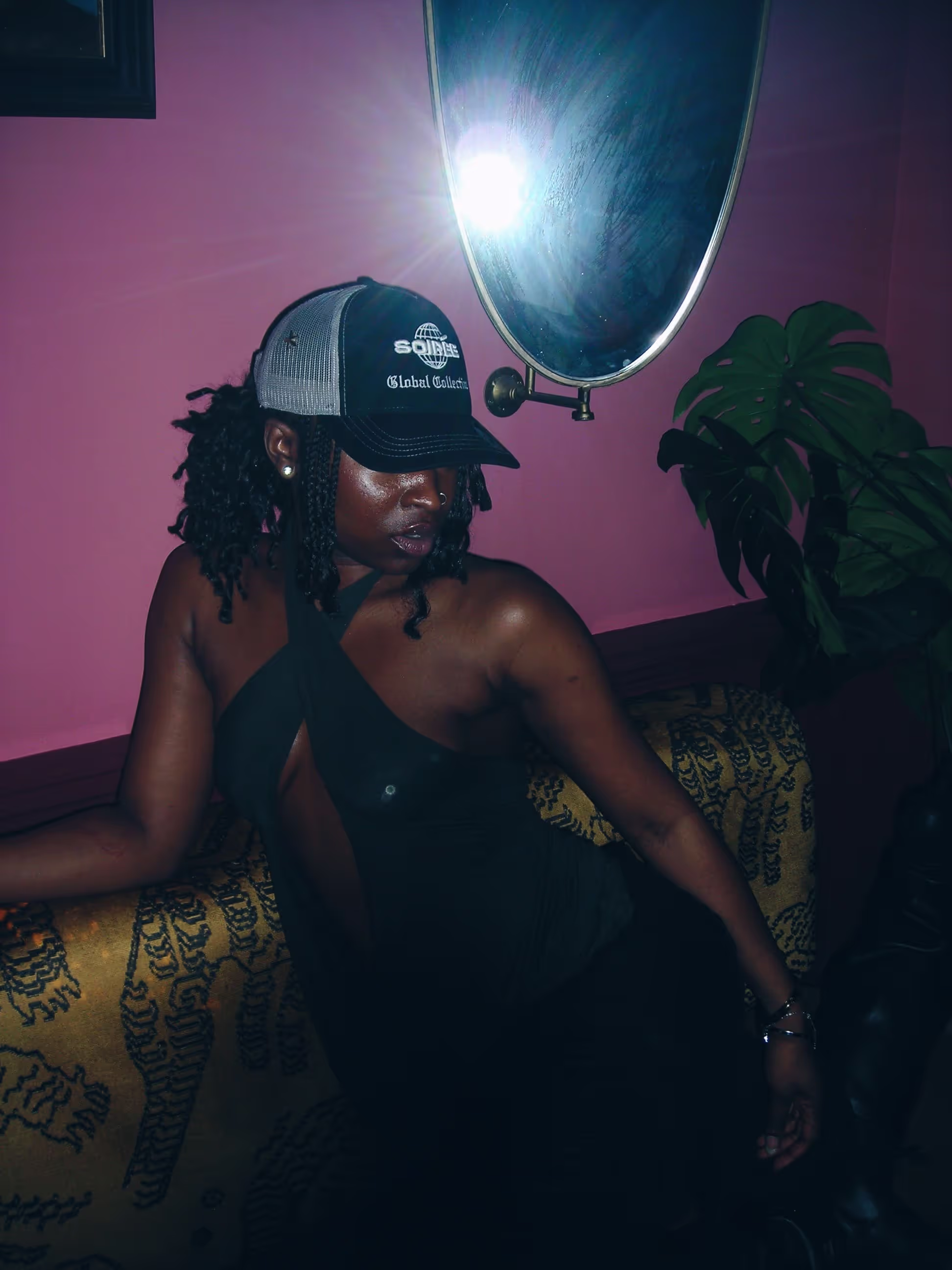 A trendy young woman posing with Soirée's branded cap at a collaboration party by Soirée, Doppelgängers, and Serene Collective at the library in London, UK