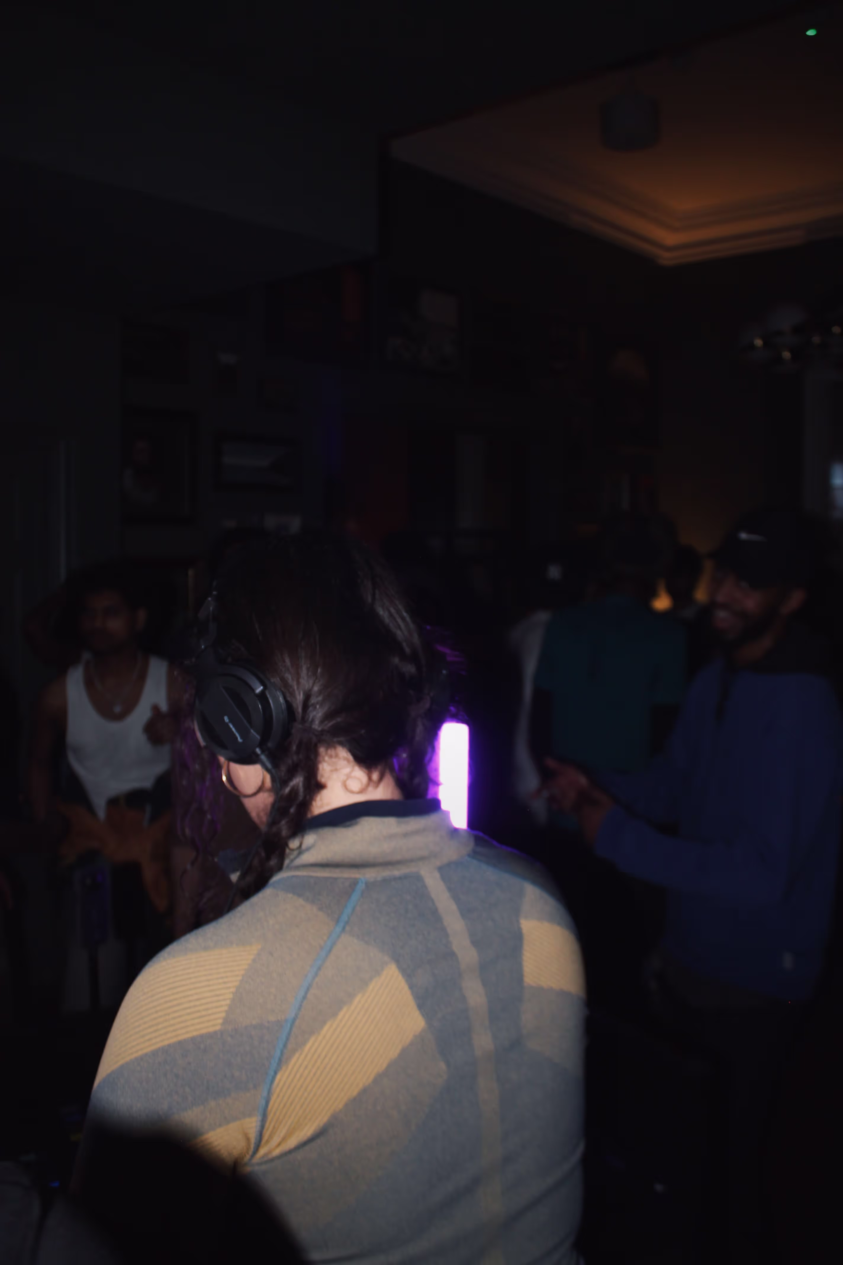 A DJ woman playing music with people dancing in the front at a collaboration party by Soirée, Doppelgängers, and Serene Collective at the library in London, UK