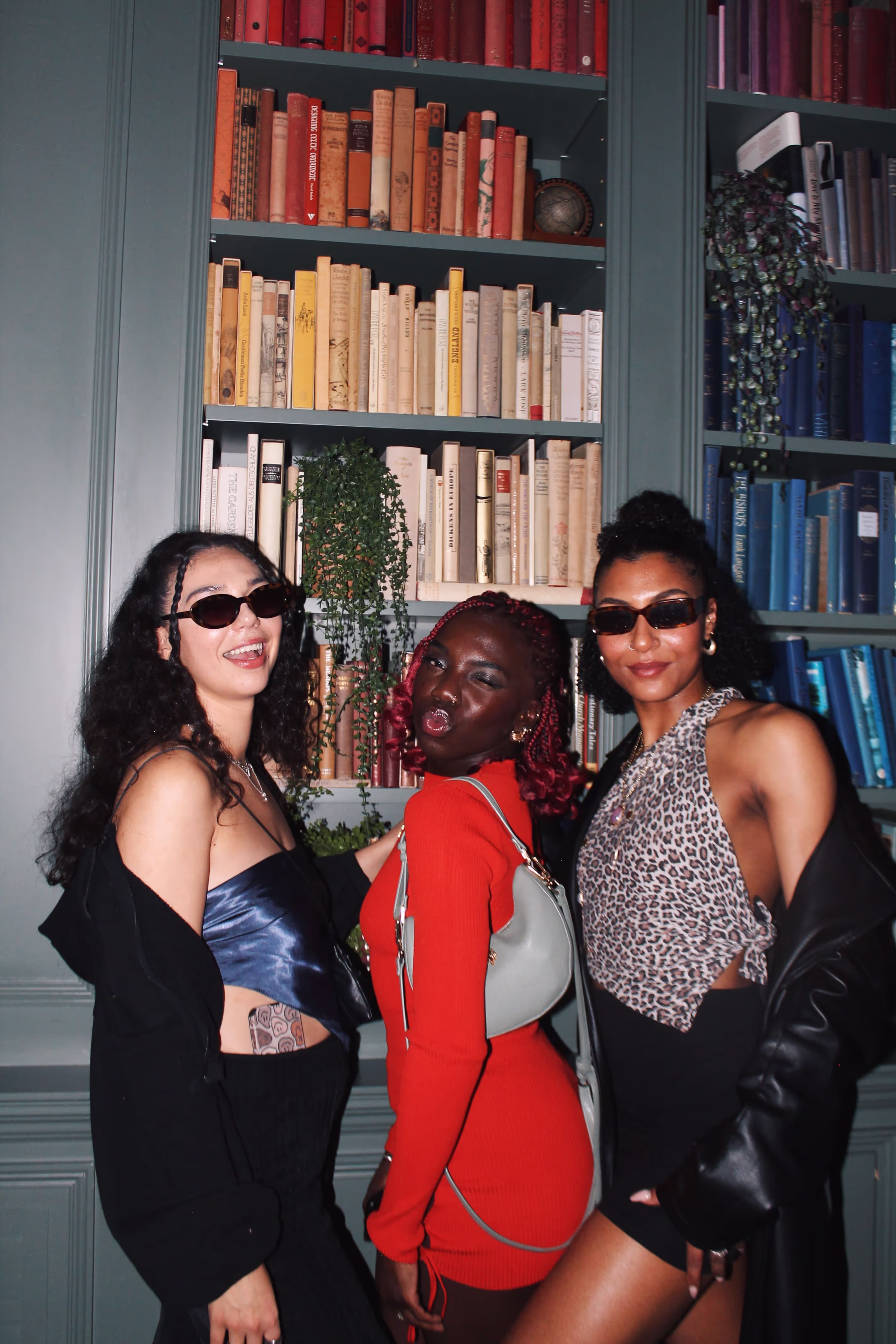Three young women in modern outfits posing at a collaboration party by Soirée, Doppelgängers, and Serene Collective at the library in London, UK