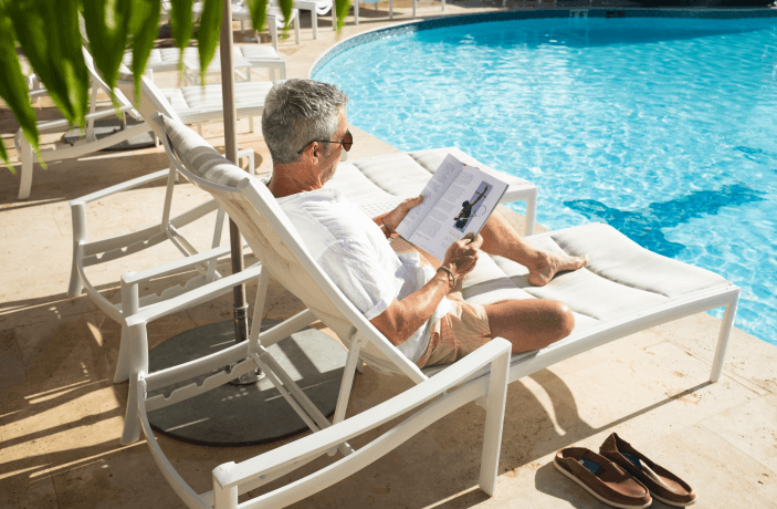 A man reading a book near the pool relaxing this summer at Wyndham Rio Mar