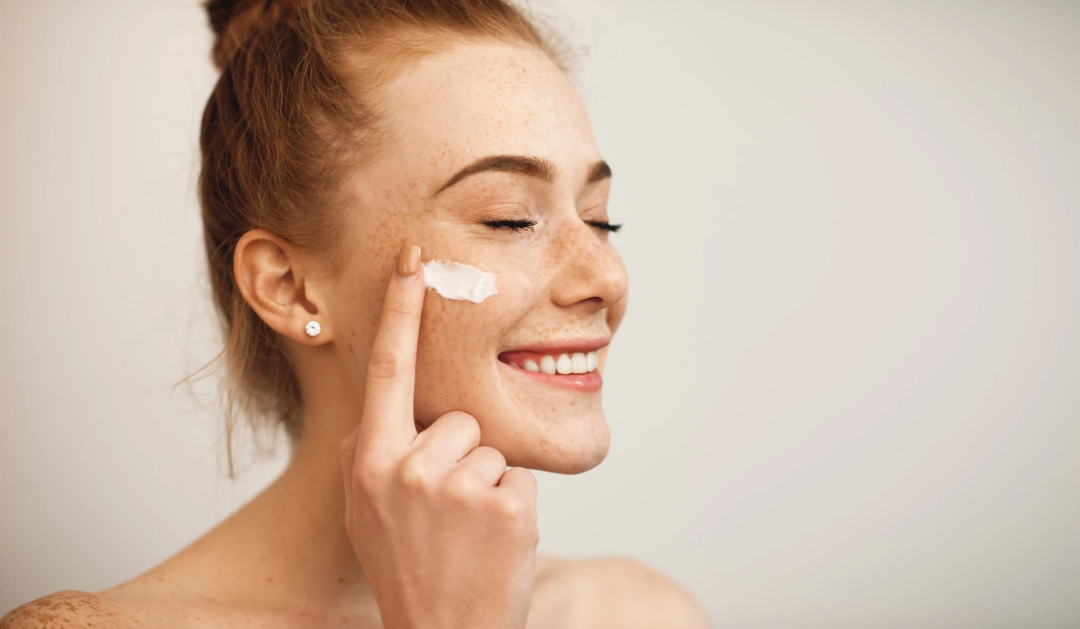 Woman smiling while putting skin care