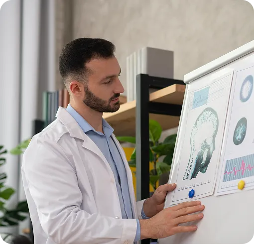 Doctor in a lab coat reviewing brain scan images on a presentation board.
