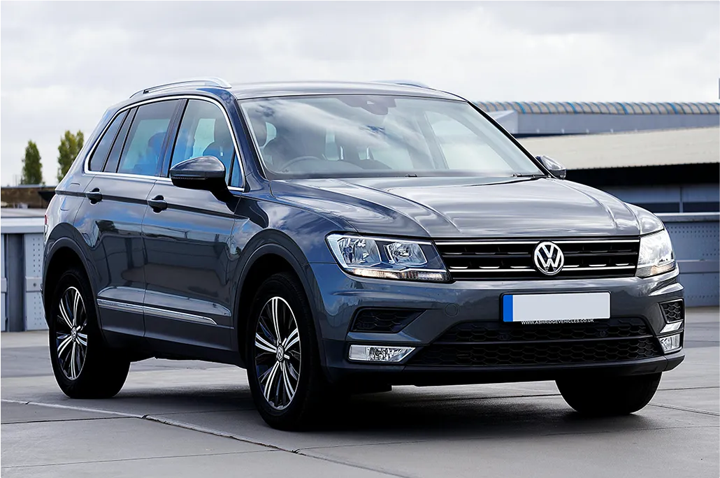 Dark gray Volkswagen SUV parked on a concrete surface with a modern industrial building in the background.