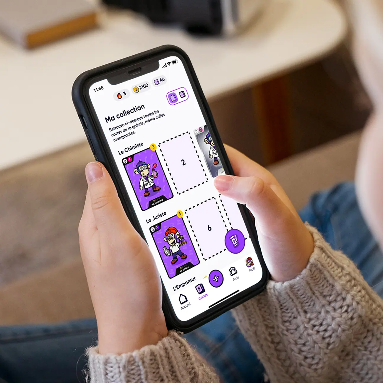 Personne tenant un smartphone affichant une collection de cartes numériques avec des personnages de singes costumés.