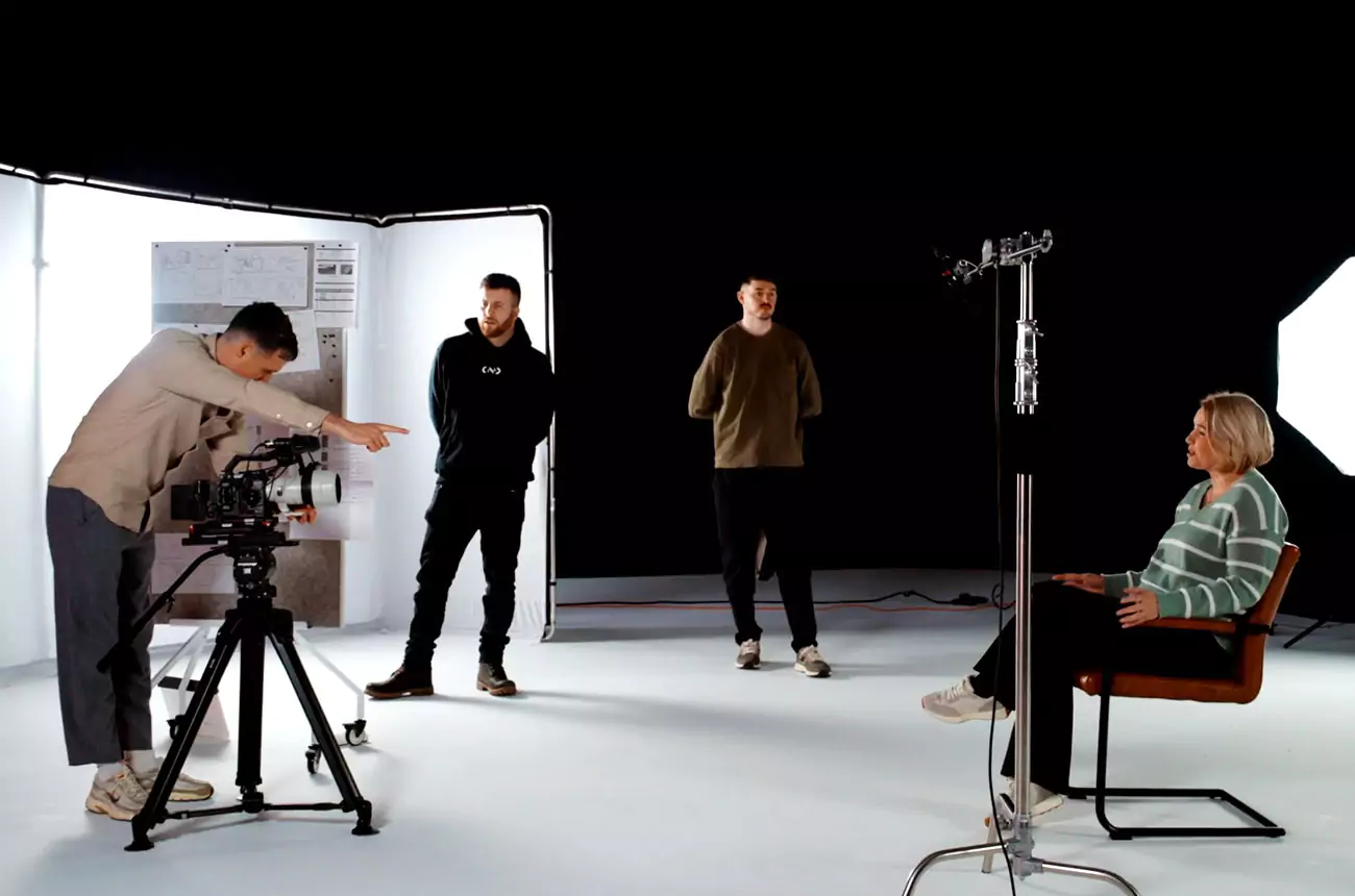 GNG Studios director giving on-set direction during a video shoot, with crew observing and subject seated under studio lights.