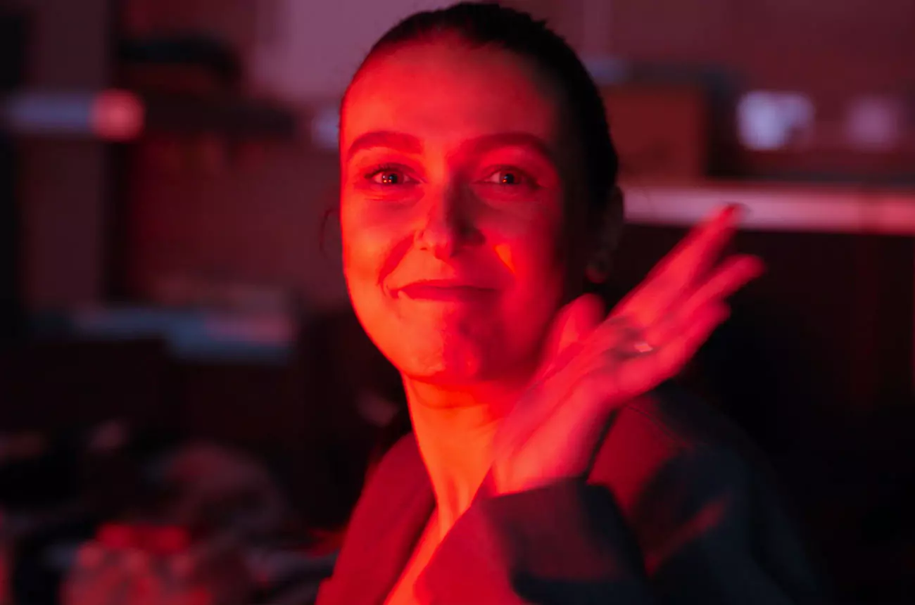 Fiona from GNG Studios giving a wave in warm red lighting during an evening set wrap-up.