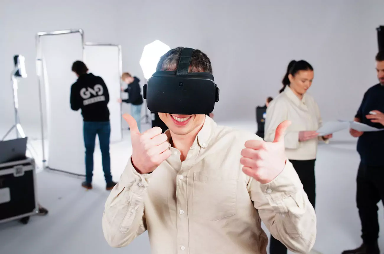 Sean from GNG Studios trying on VR headset on set, giving a thumbs-up with the team prepping in the background.