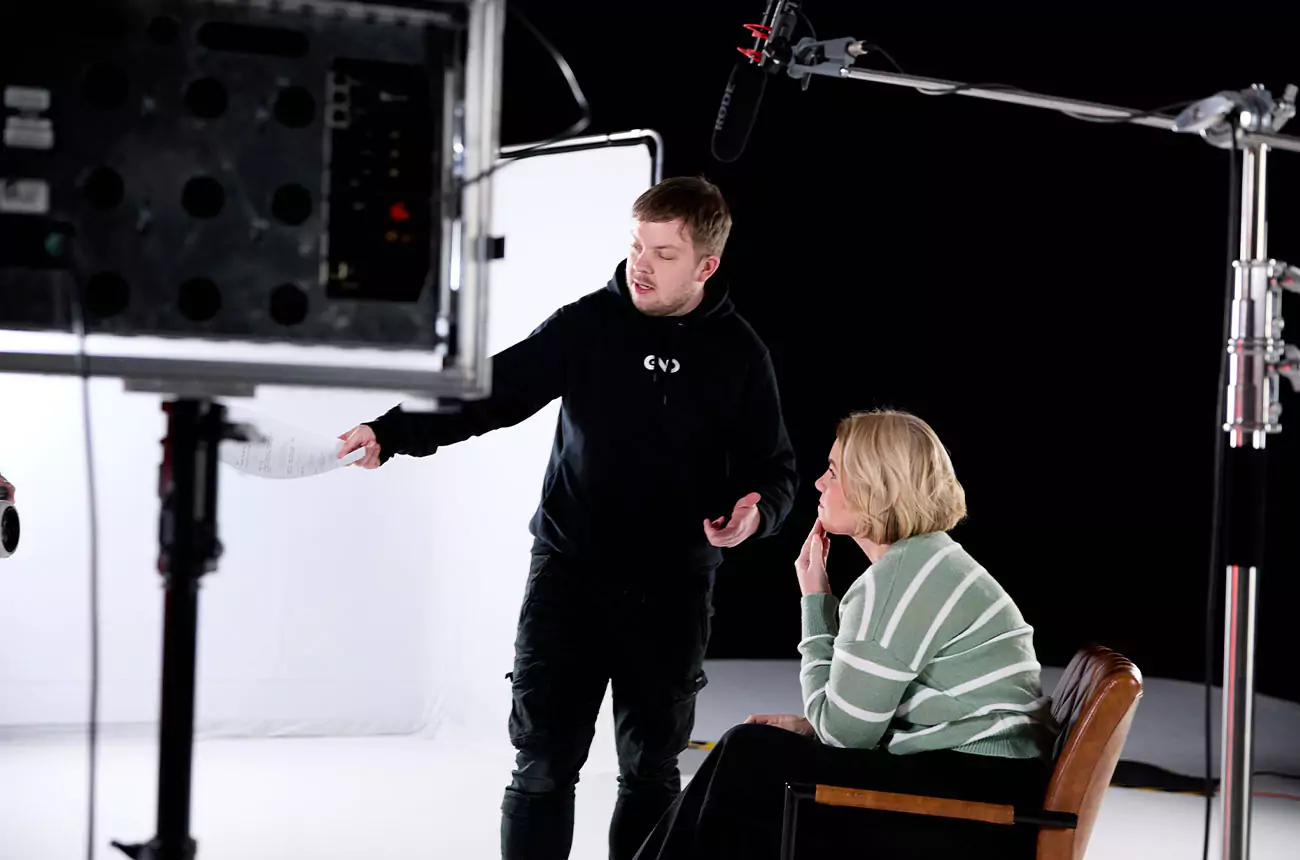 Shoot Director briefing a client before filming during a GNG Studios video shoot, with lighting and mic setup in frame.