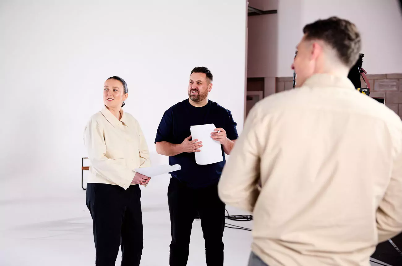 GNG Studios team reviewing scripts and discussing the next setup on a video production set.