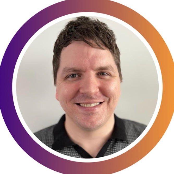Smiling man with short brown hair wearing a black and gray collared shirt, inside a circular frame with a purple to orange gradient border.