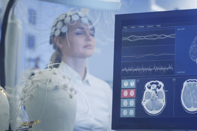Une participante équipée d'un casque d'électroencéphalographie devant un écran affichant ses ondes cérébrales et des coupes d'imagerie