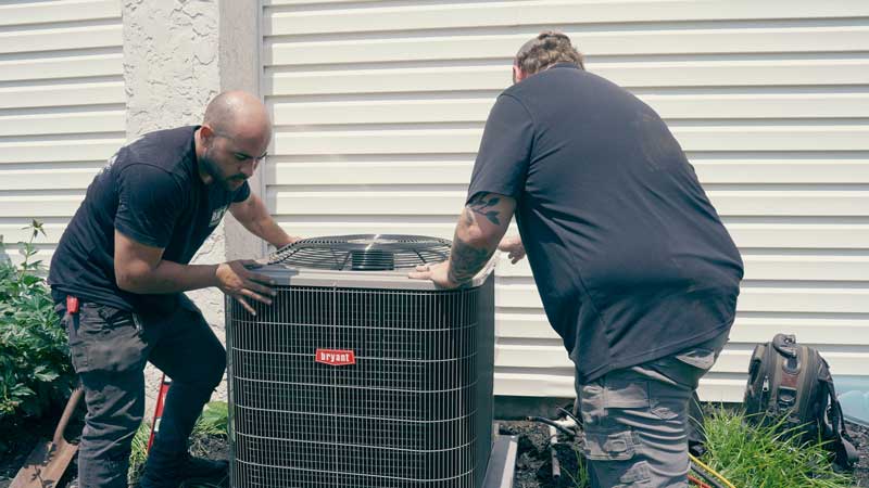 Air Conditioning Unit HVAC Installation - two technicians installing the unit