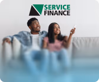 Two people on couch with remote under 'Service Finance' logo featuring green and black triangle