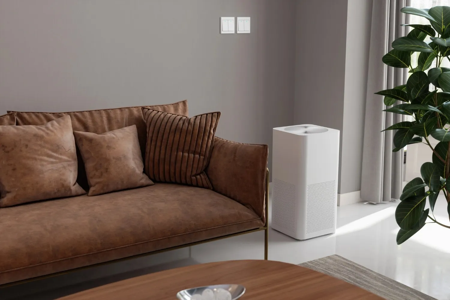 A modern, white rectangular air purifier stands on a shiny white floor in a living room, positioned between a brown sofa with pillows and a large green plant.