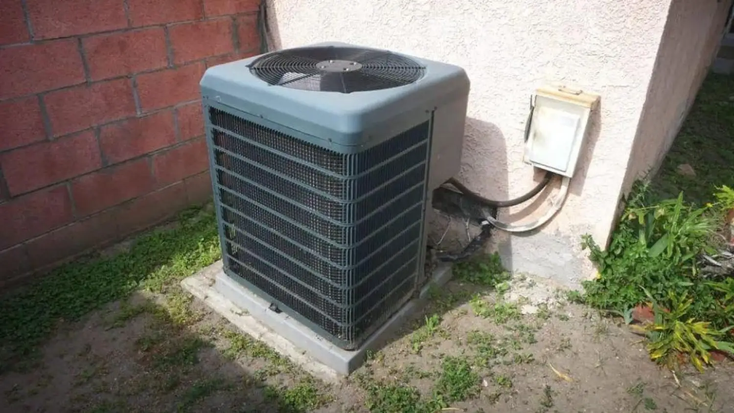 A heat pump installed in front of a residential house, showcasing its outdoor unit and surrounding landscaping.