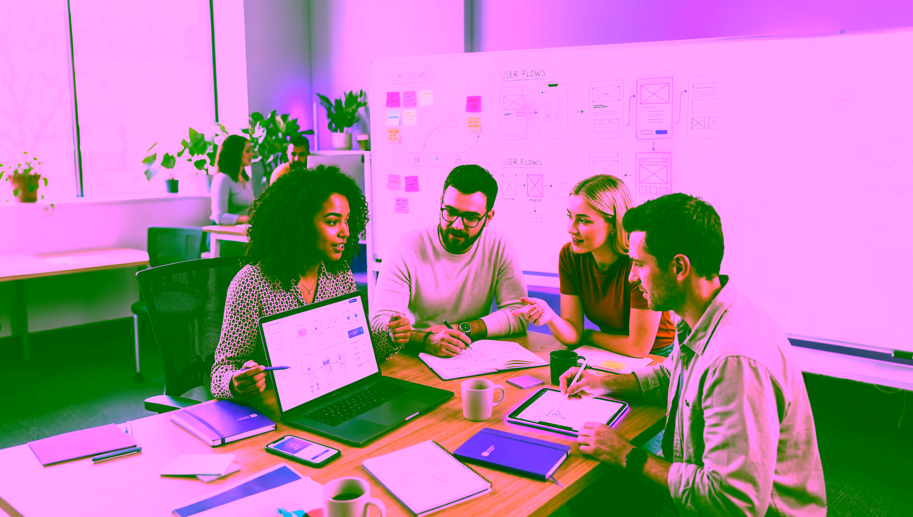 4 Personen sitzen in einem Meeting und sprechen über UX Design
