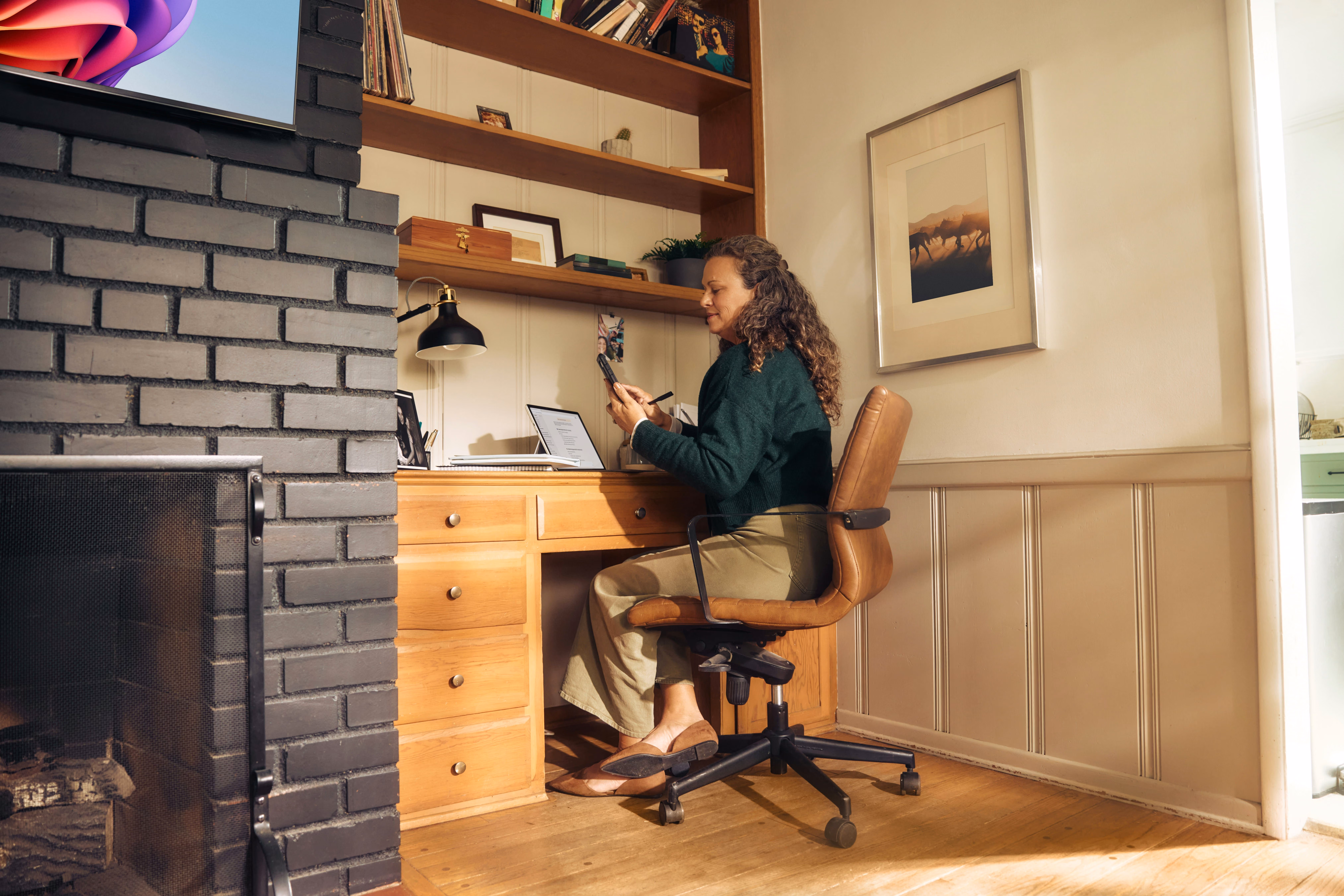 Femme assise à son bureau, remplissant un formulaire en ligne sur son téléphone.