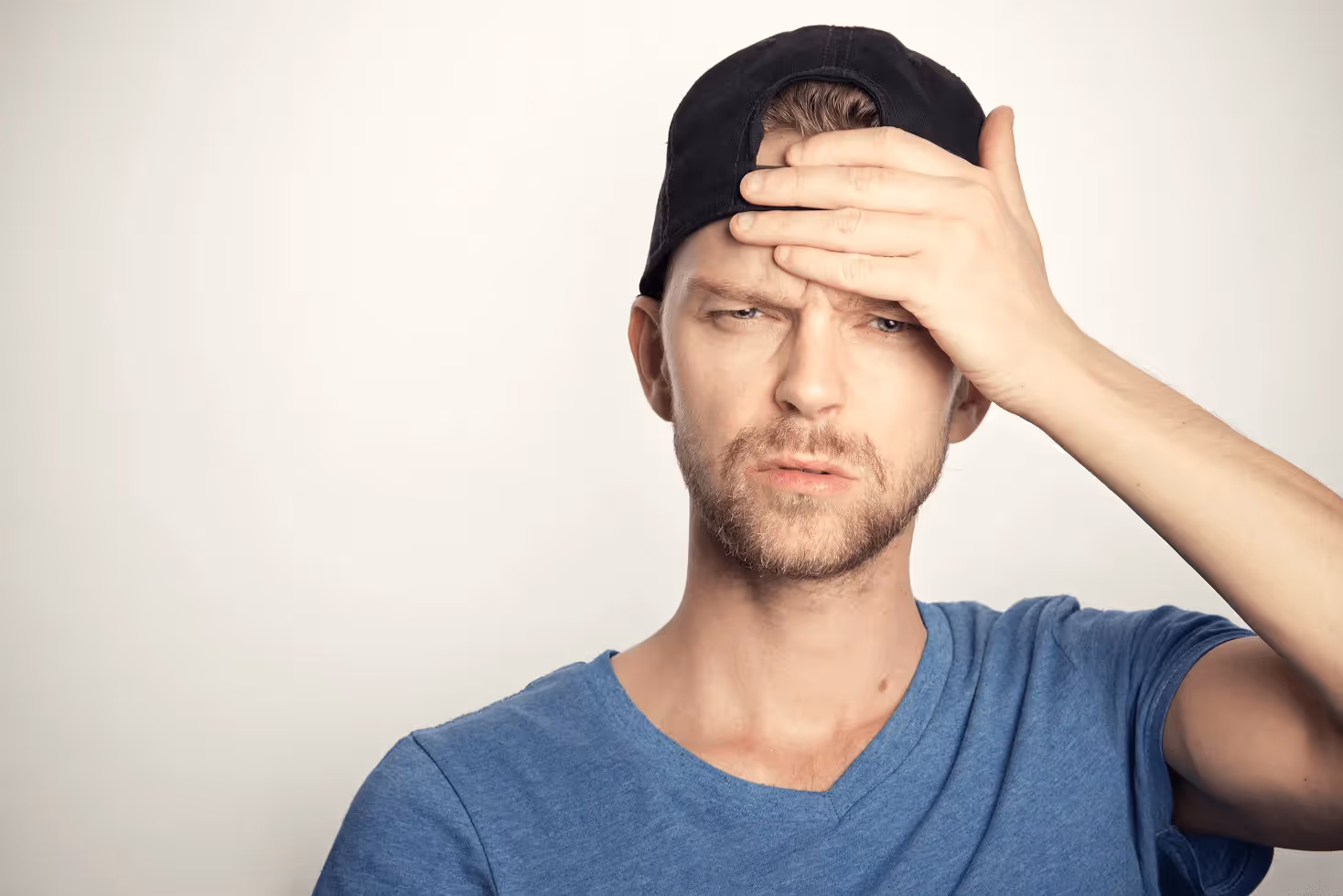 Man in blue crew neck shirt covering his face
