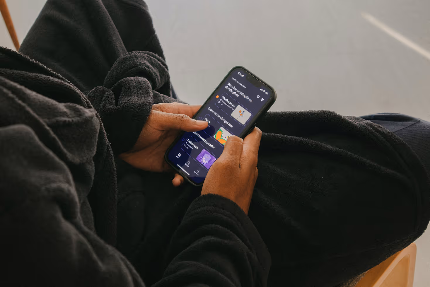 A person sitting on a chair holding a cell phone