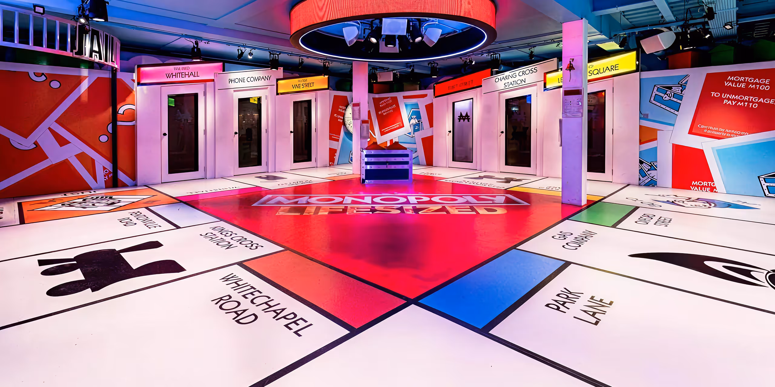 Colorful immersive room decorated as a giant Monopoly game board with property names and cards on walls and floors.