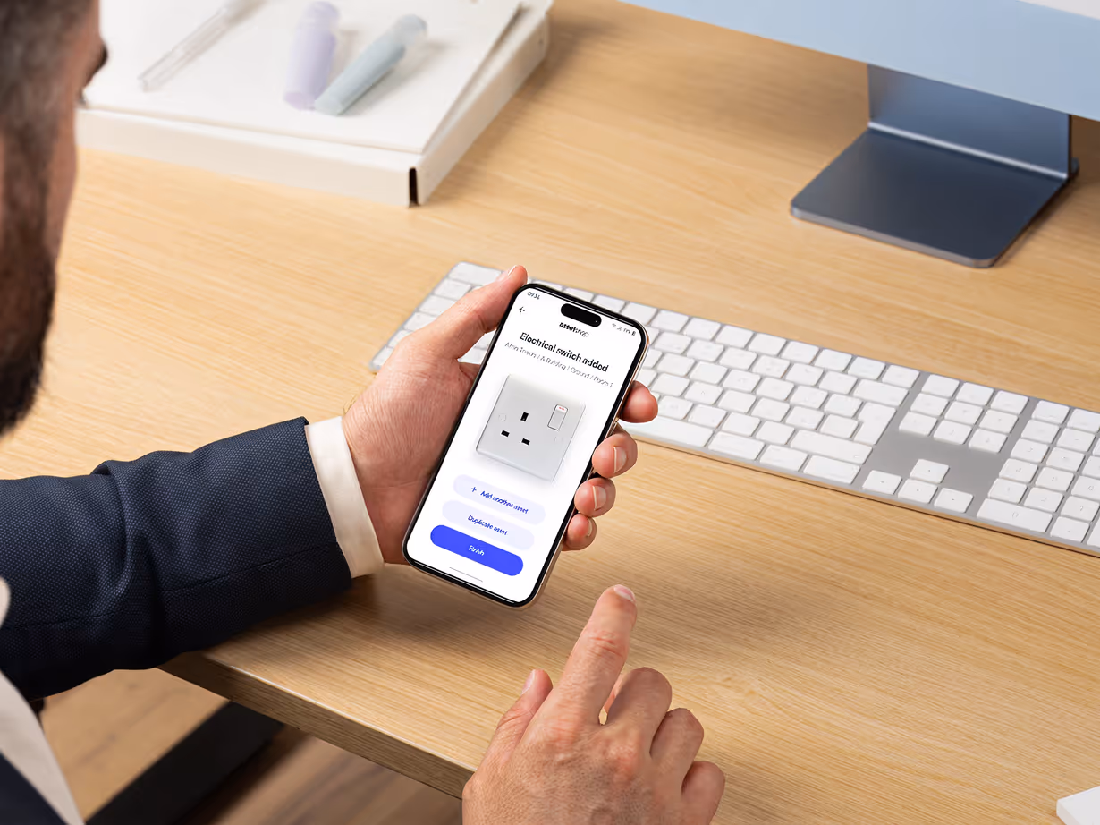 Person holding a smartphone displaying an app for recognising switch socket.