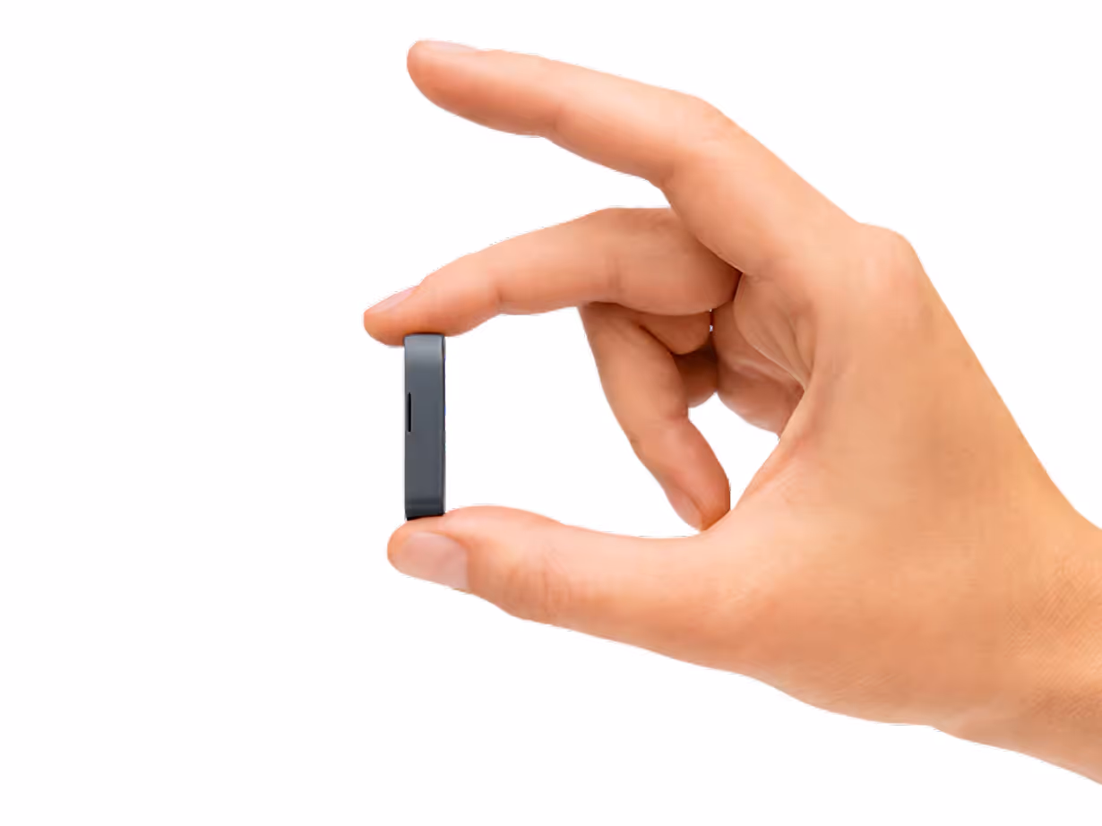 Hand holding a small, slim rectangular black electronic device between thumb and forefinger.