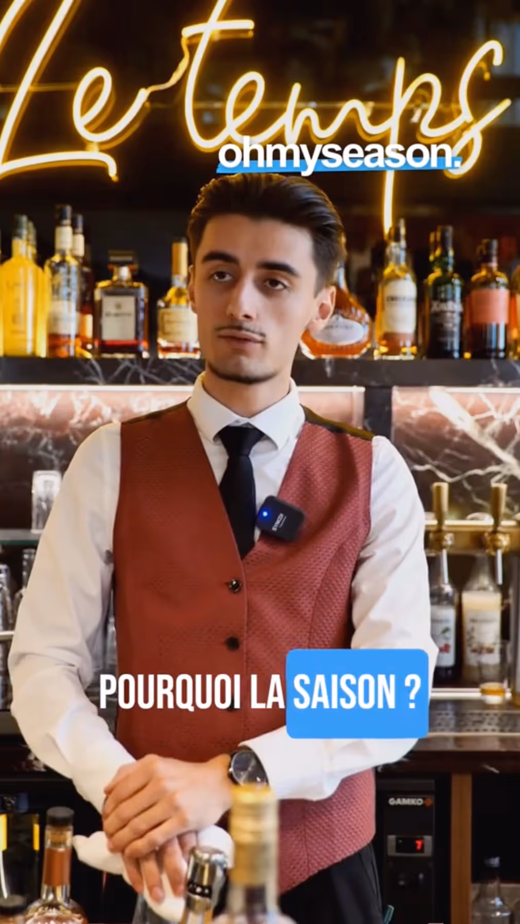 Barman élégant en tenue professionnelle dans un établissement, partenaire d'Ohmyseason pour l'emploi saisonnier. Cette image illustre les opportunités de jobs saisonniers de barman dans l'hôtellerie haut de gamme. Le travail saisonnier en bar permet d'apprendre la mixologie et de maîtriser l'art du service des boissons dans un environnement prestigieux. Les emplois saisonniers logés de barman offrent une formation complète en cocktails et gestion de bar. "Pourquoi la saison ?" - car l'emploi saisonnier de barman dans des établissements de qualité permet d'acquérir une expertise reconnue et des compétences transférables. Trouvez votre poste de barman saisonnier avec nos partenaires sur Ohmyseason.fr.