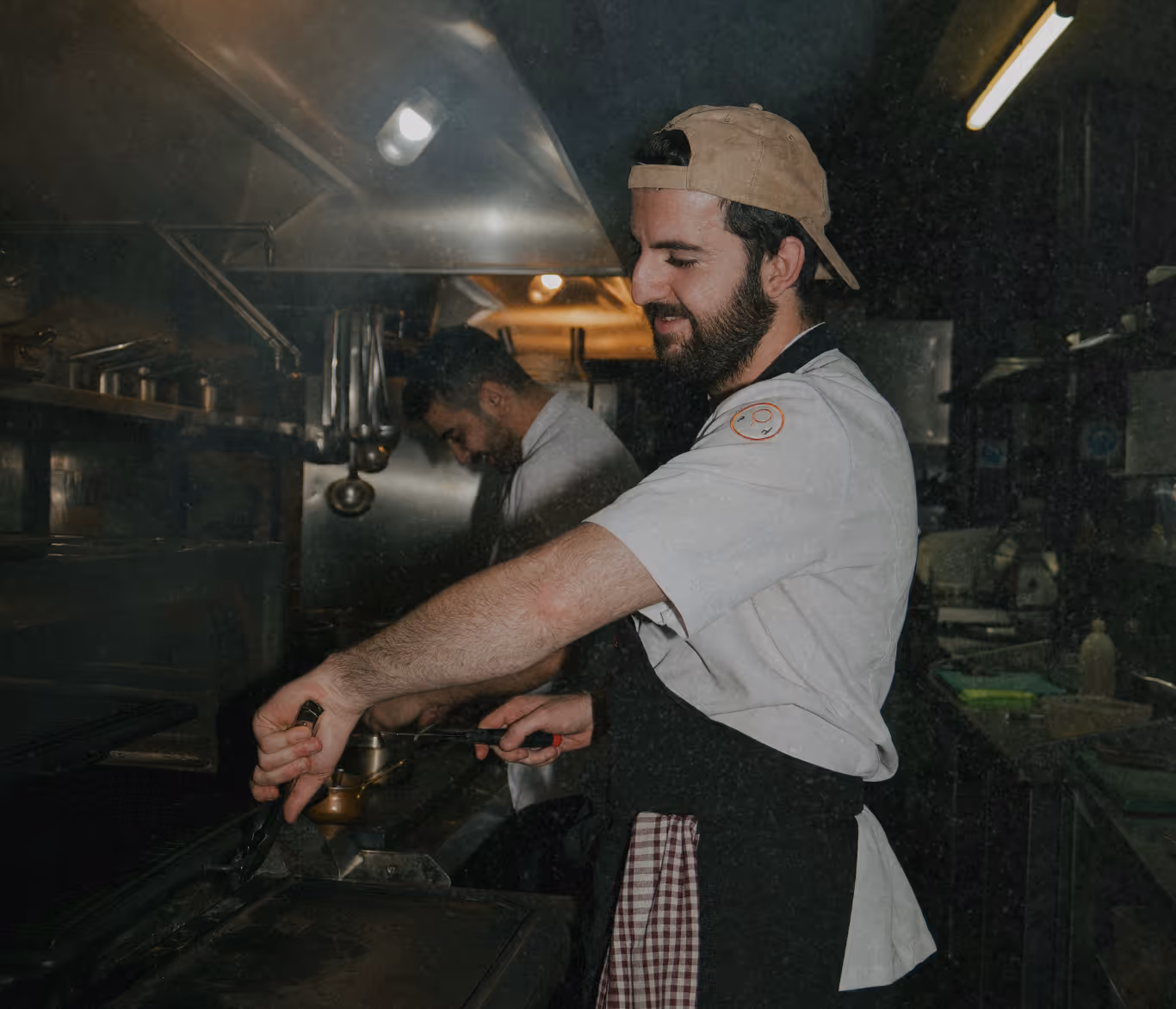 Cuisinier professionnel en action dans une cuisine de restaurant, illustrant les nombreuses opportunités d'emploi saisonnier dans la restauration. Les jobs saisonniers de cuisinier sont très recherchés pendant la haute saison touristique, offrant une excellente expérience dans les métiers de bouche. Ce type de travail saisonnier permet d'acquérir des compétences culinaires précieuses tout en bénéficiant souvent d'un emploi saisonnier logé dans les stations balnéaires et de ski. Les restaurants, hôtels et établissements touristiques proposent régulièrement des postes de cuisinier en emploi saisonnier, particulièrement recherchés par les étudiants et professionnels de la restauration.