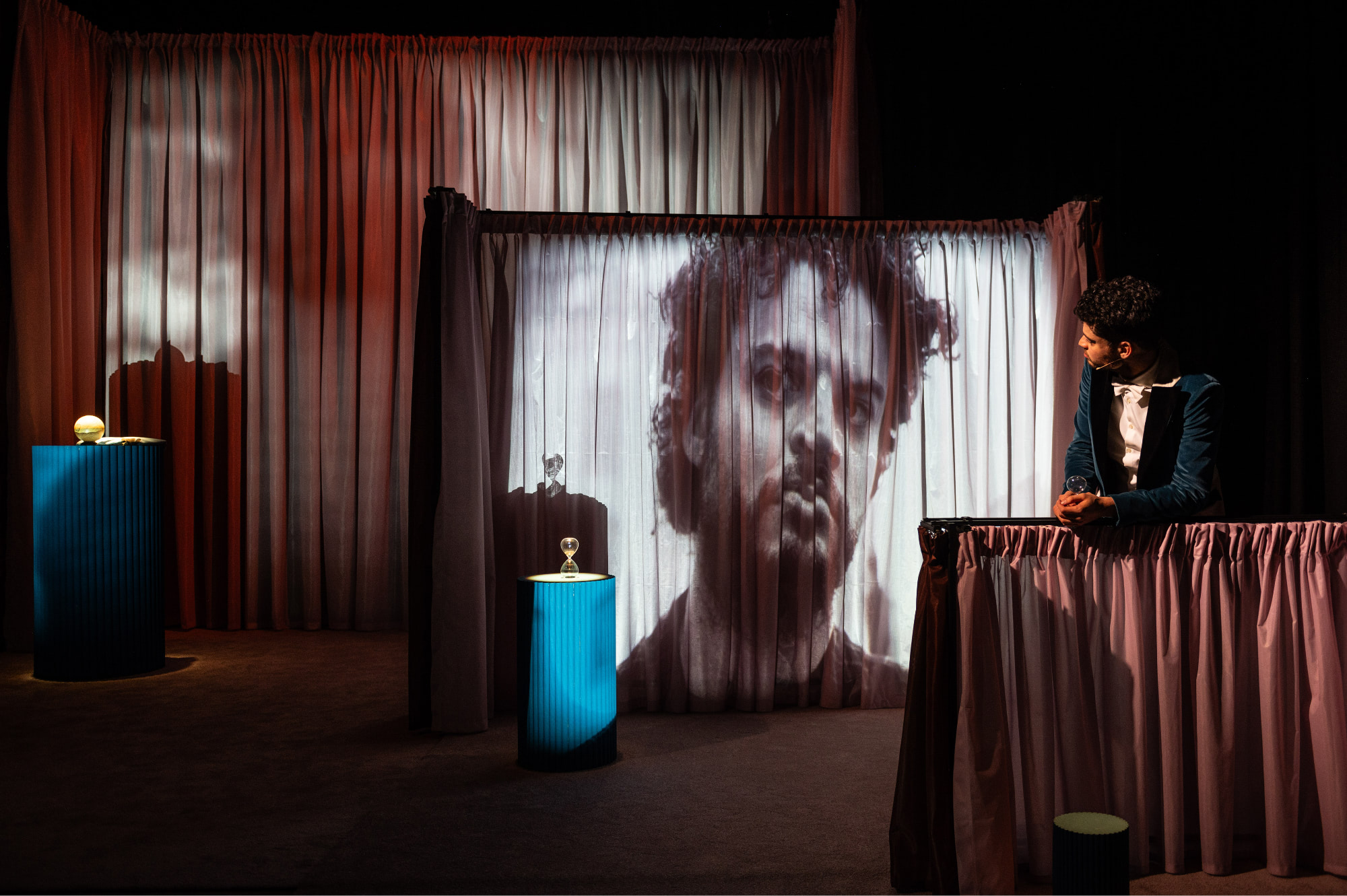 Theaterpodium met verschillende stands en doeken waar een video op wordt geprojecteerd