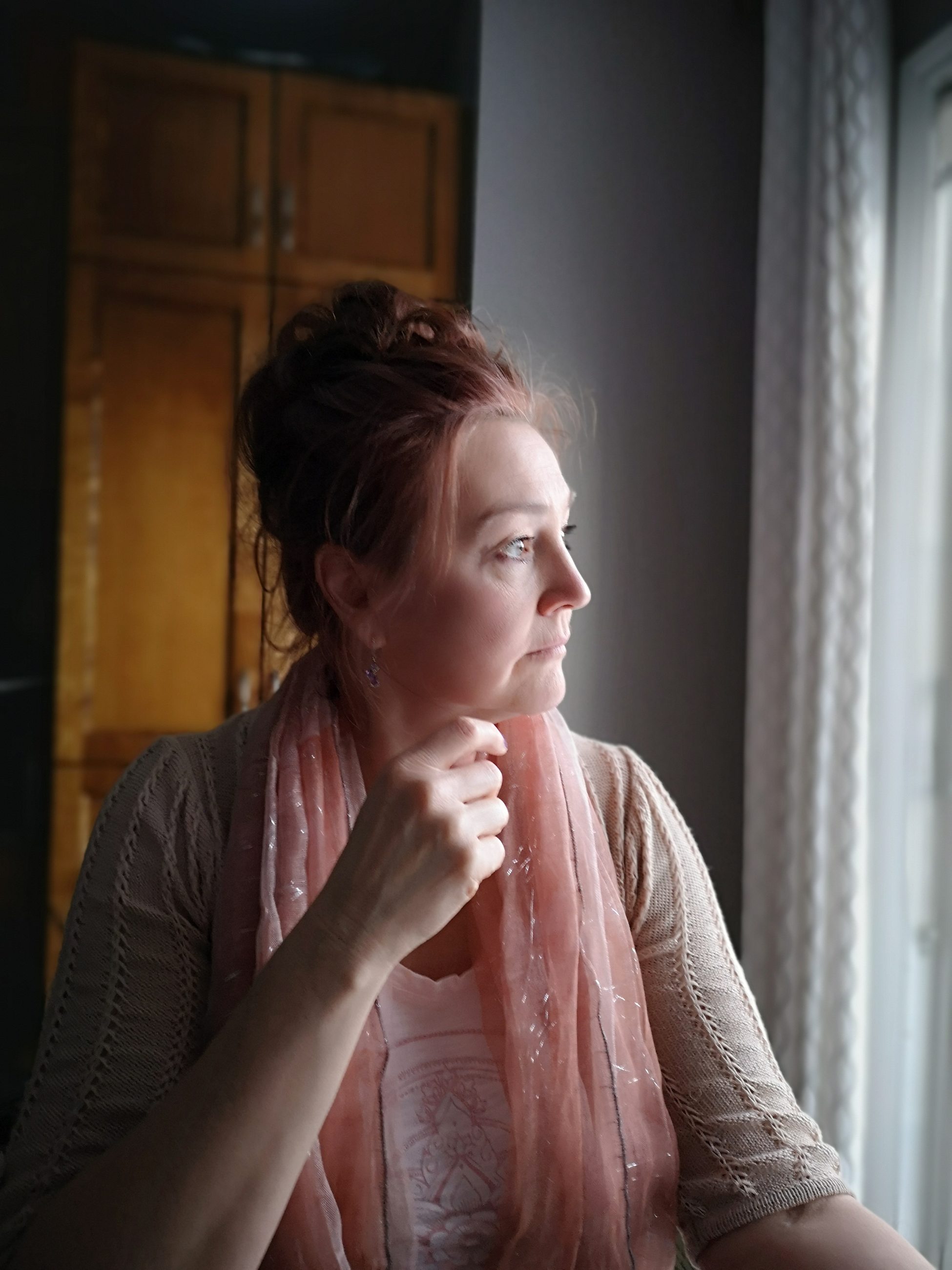 Frau blickt nachdenklich aus dem Fenster