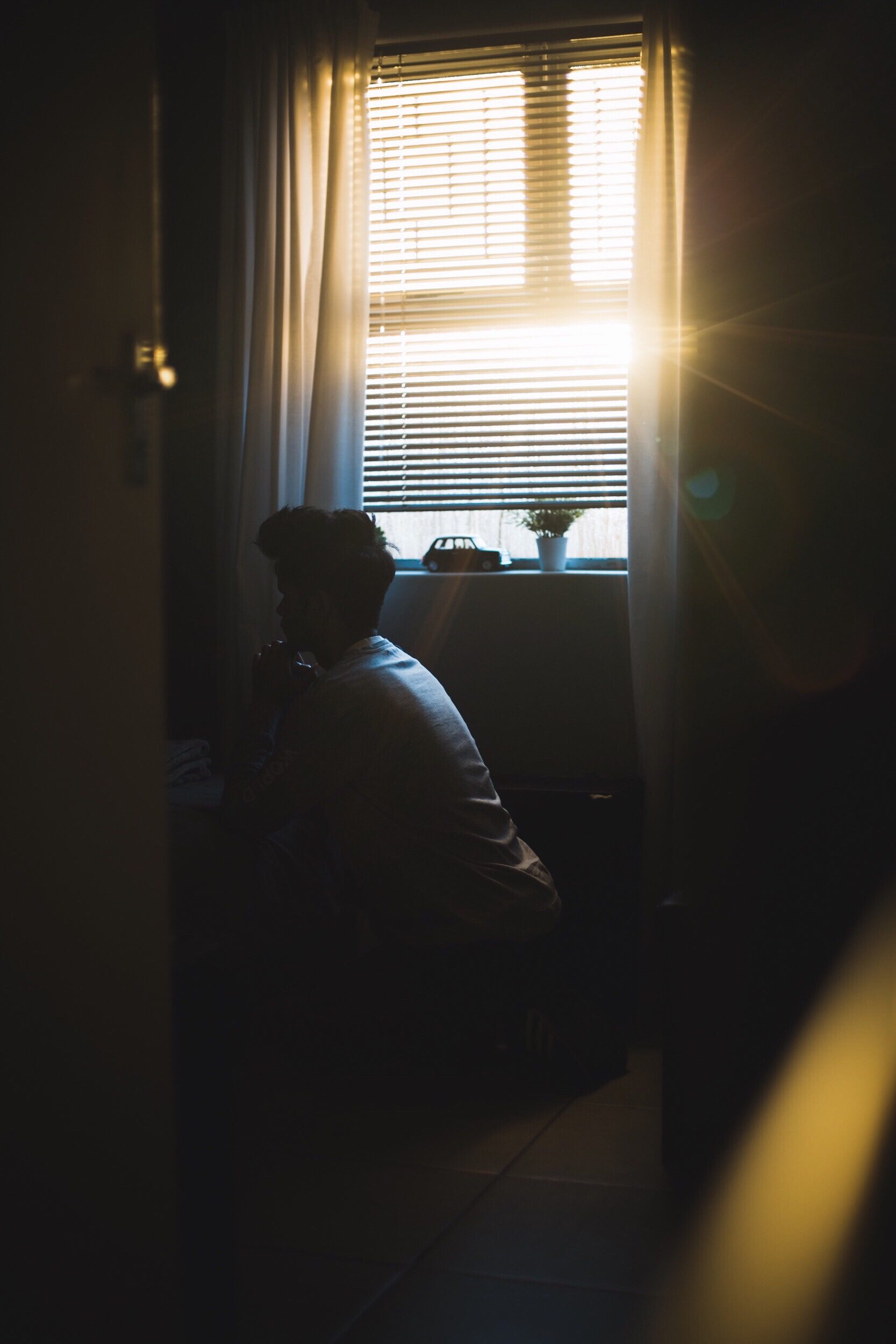 Silhouette einer Person am hellen Fenster in dunklem Raum