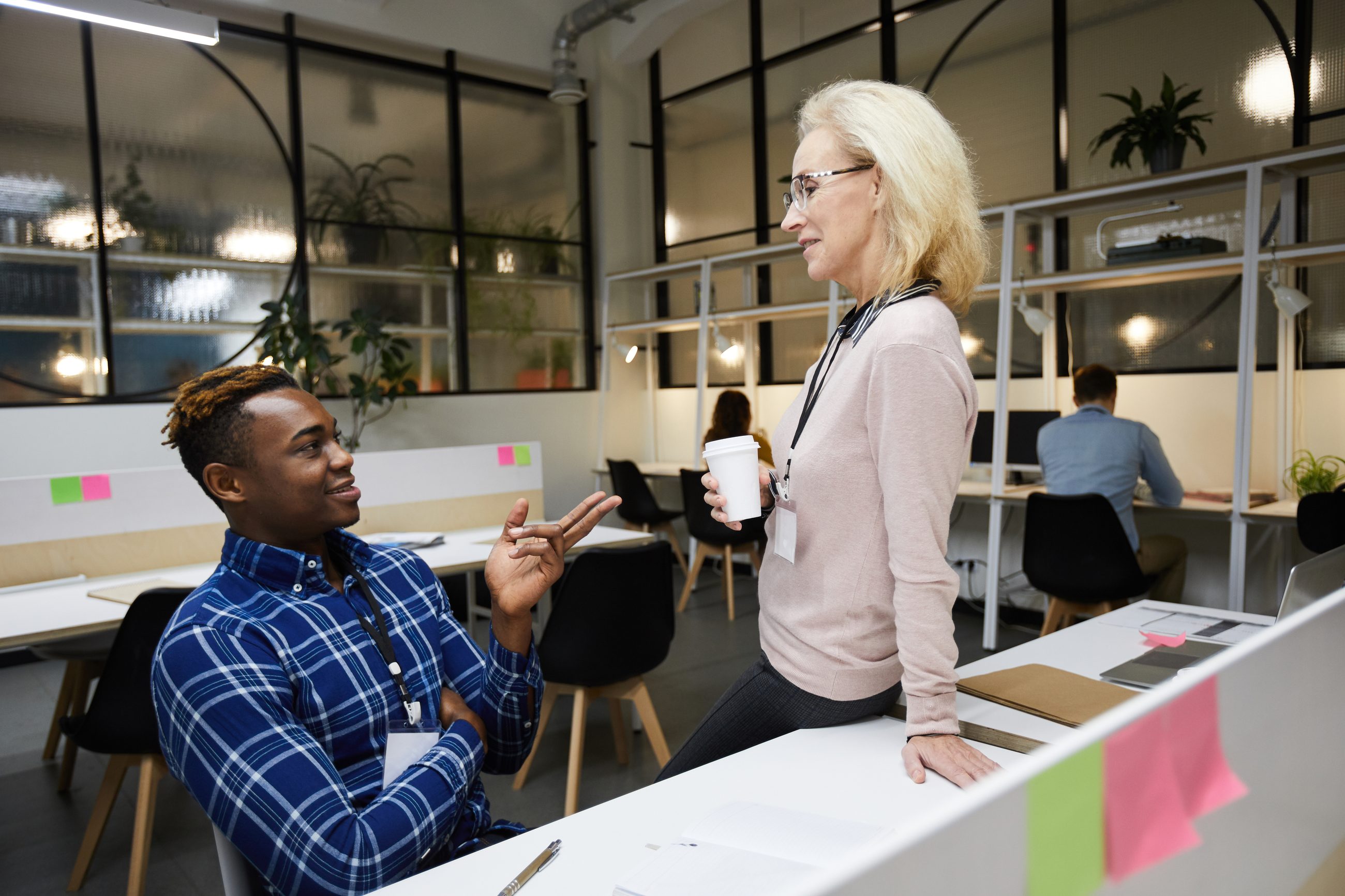 Zwei Kolleg:innen im offenen Büro im Gespräch als Symbol für Feedback am Arbeitsplatz