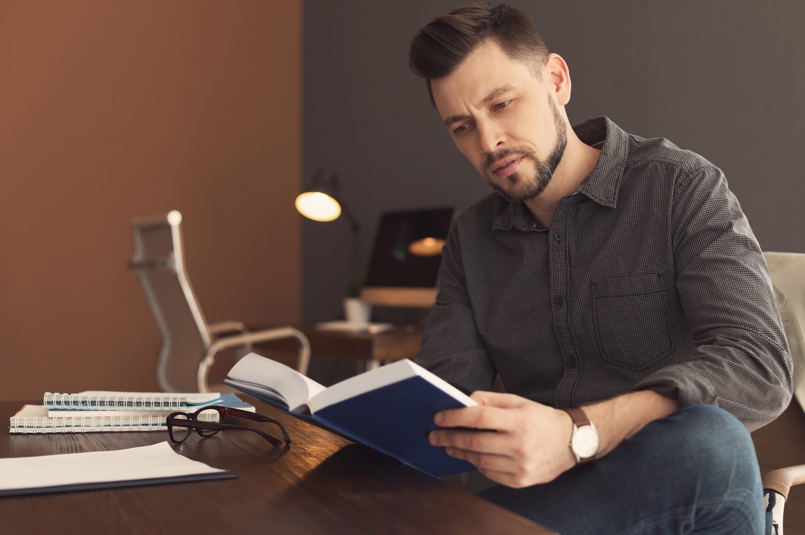 Führungskraft liest ein Buch am Schreibtisch als Symbol für fundierte Führungsliteratur