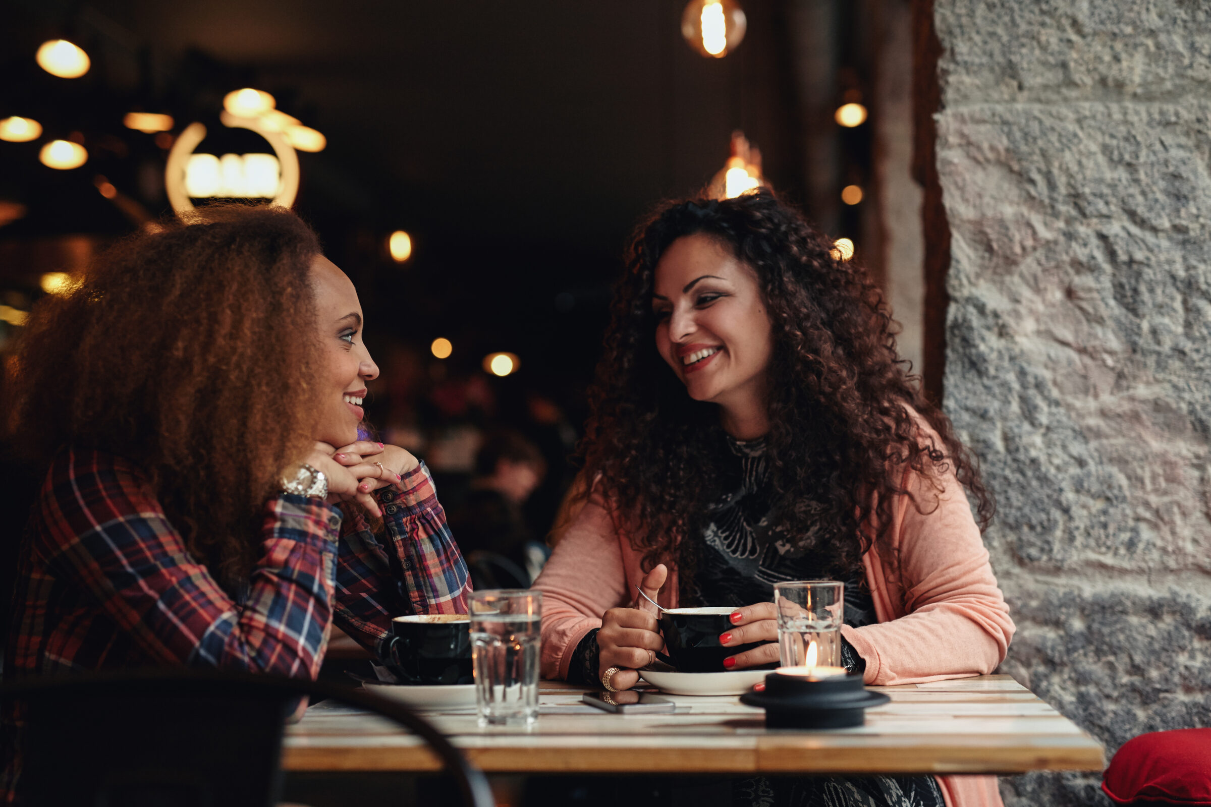 Zwei Freundinnen sitzen abends im Café und unterhalten sich vertraut – Symbolbild für echte Nähe und geteilte Zeit in Freundschaften im Erwachsenenalter