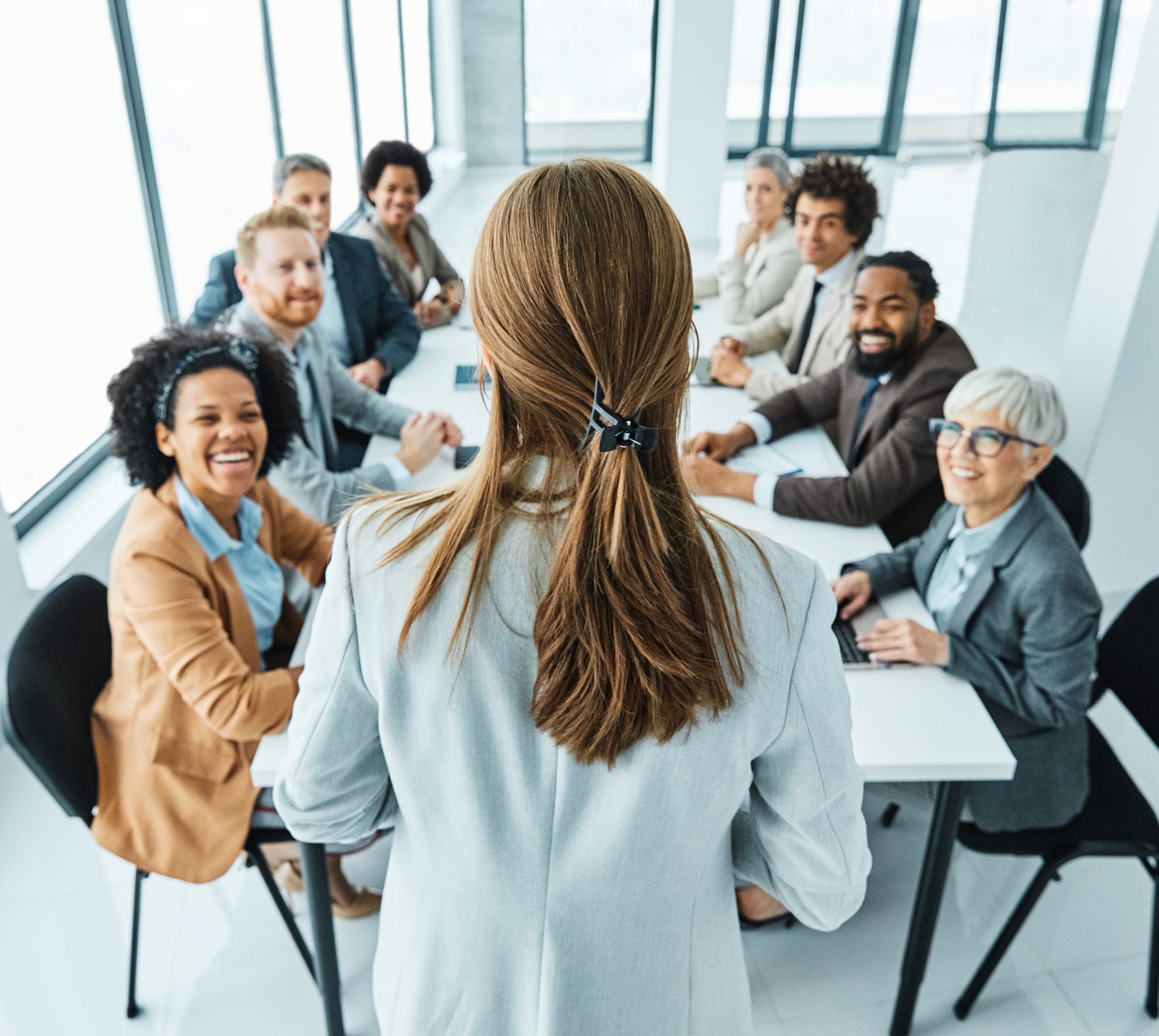 Neue Führungskraft steht vor ihrem ehemaligen Team beim ersten Meeting nach der Beförderung