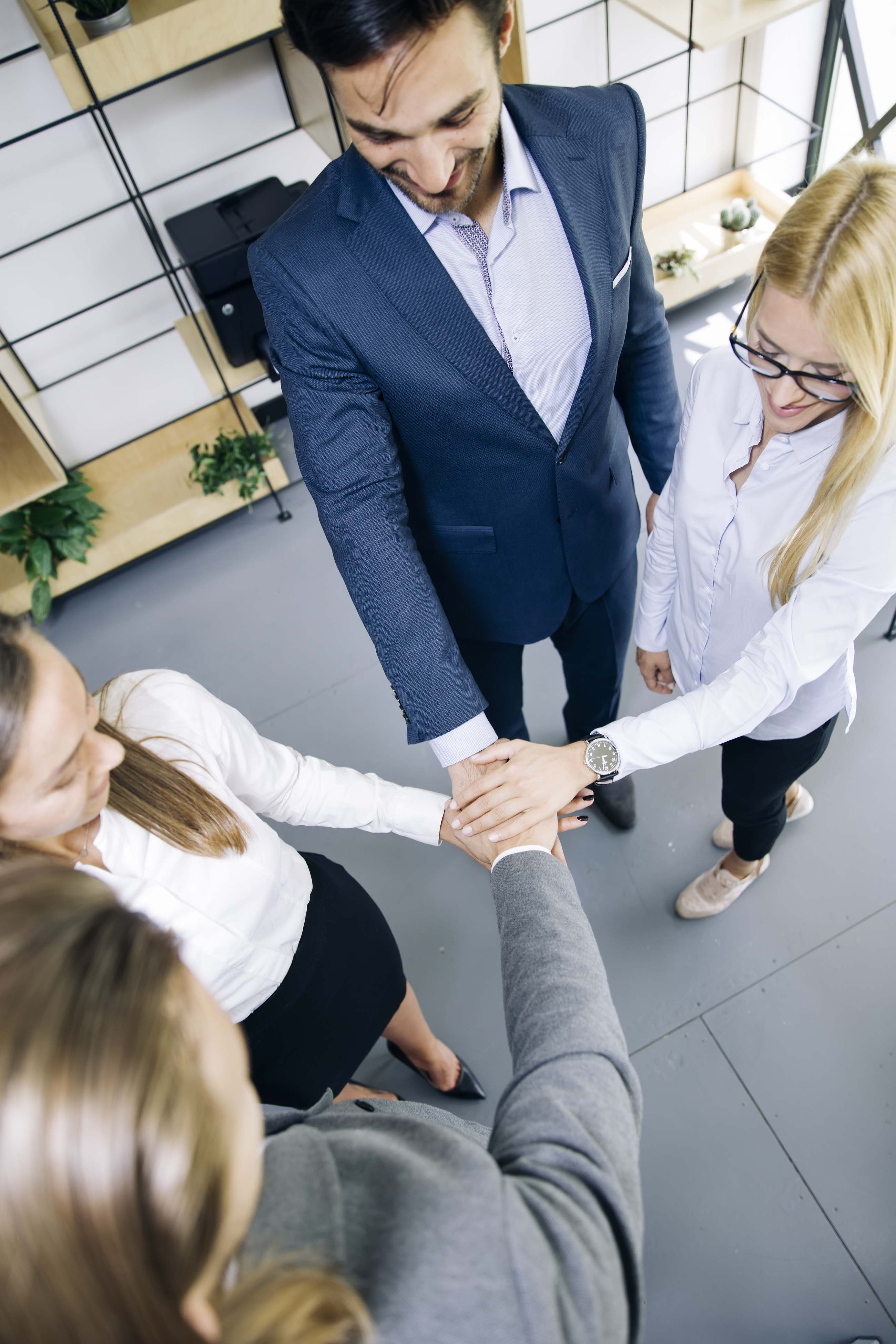 Team von Mitarbeitenden legt die Hände zusammen als Symbol für Vertrauen und Einheit im Büro