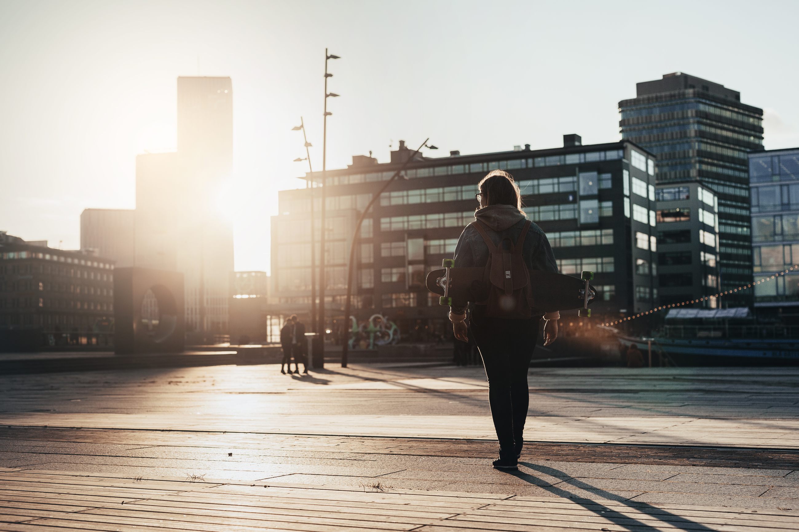 Person geht bei Morgenlicht über einen städtischen Platz als Sinnbild für den fehlenden Arbeitsweg im Homeoffice