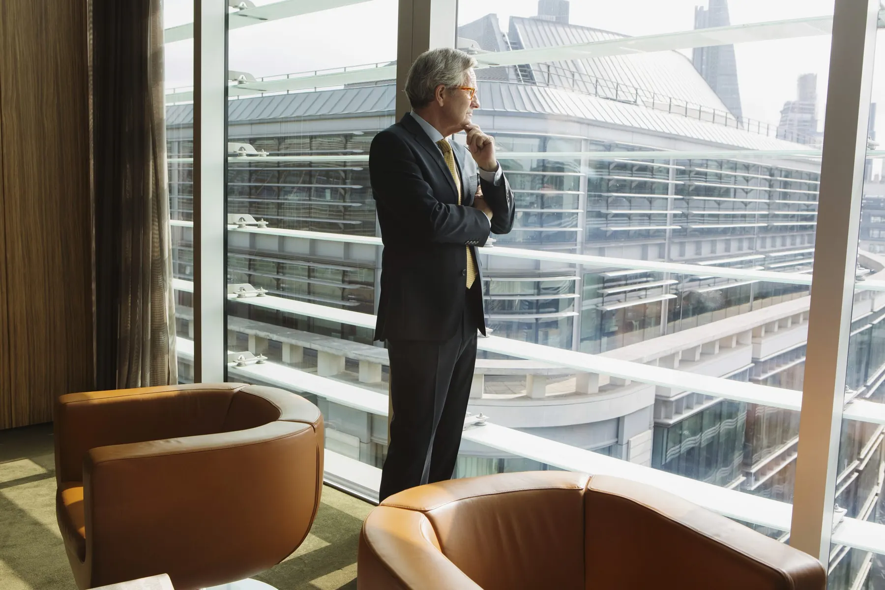 Führungskraft steht nachdenklich am Fenster einer modernen Büroetage und blickt auf die Skyline, Sinnbild für Executive Presence und Gravitas