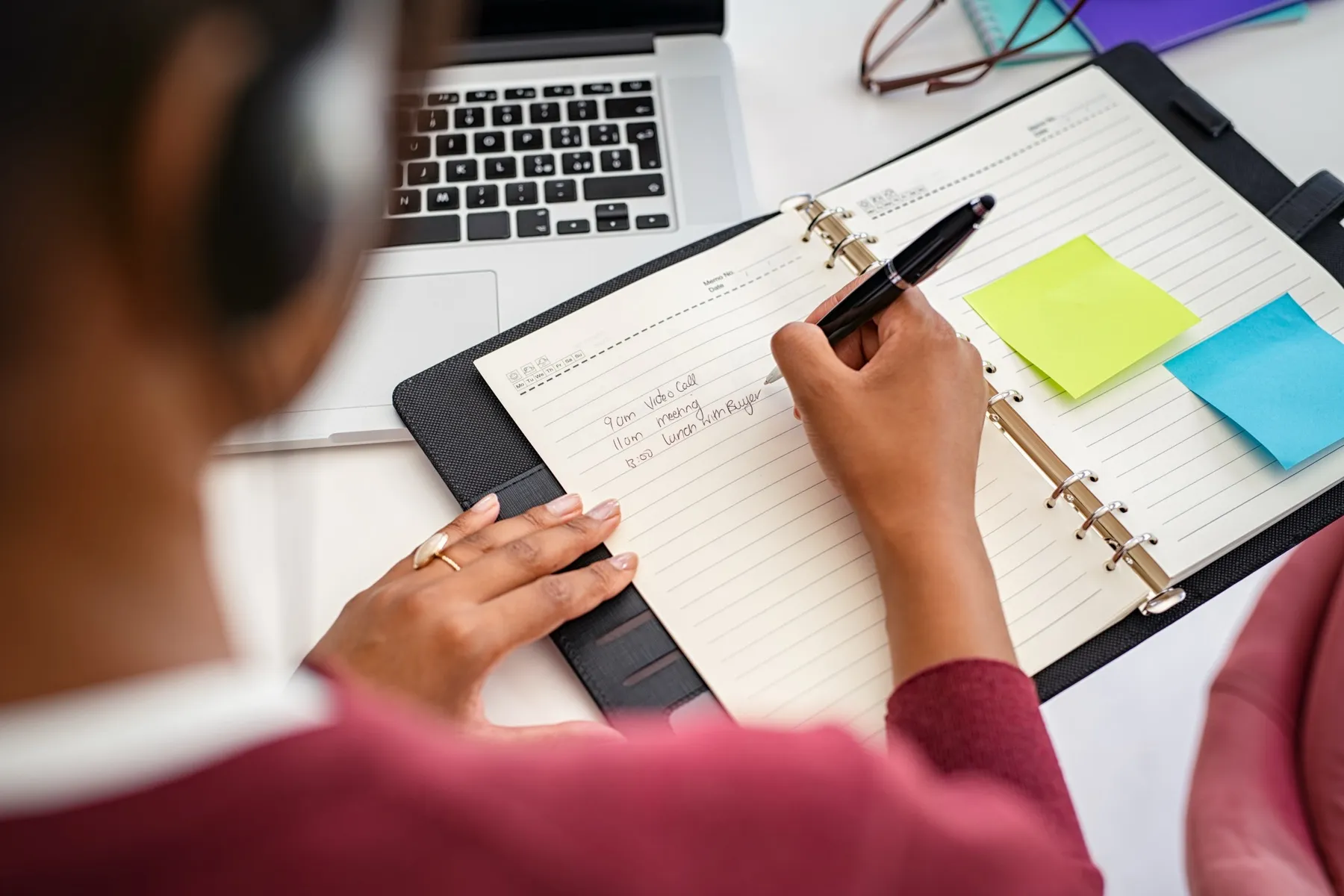Frau plant ihren Tag mit Stift und Notizbuch, Sinnbild für bewusstes Prioritäten setzen