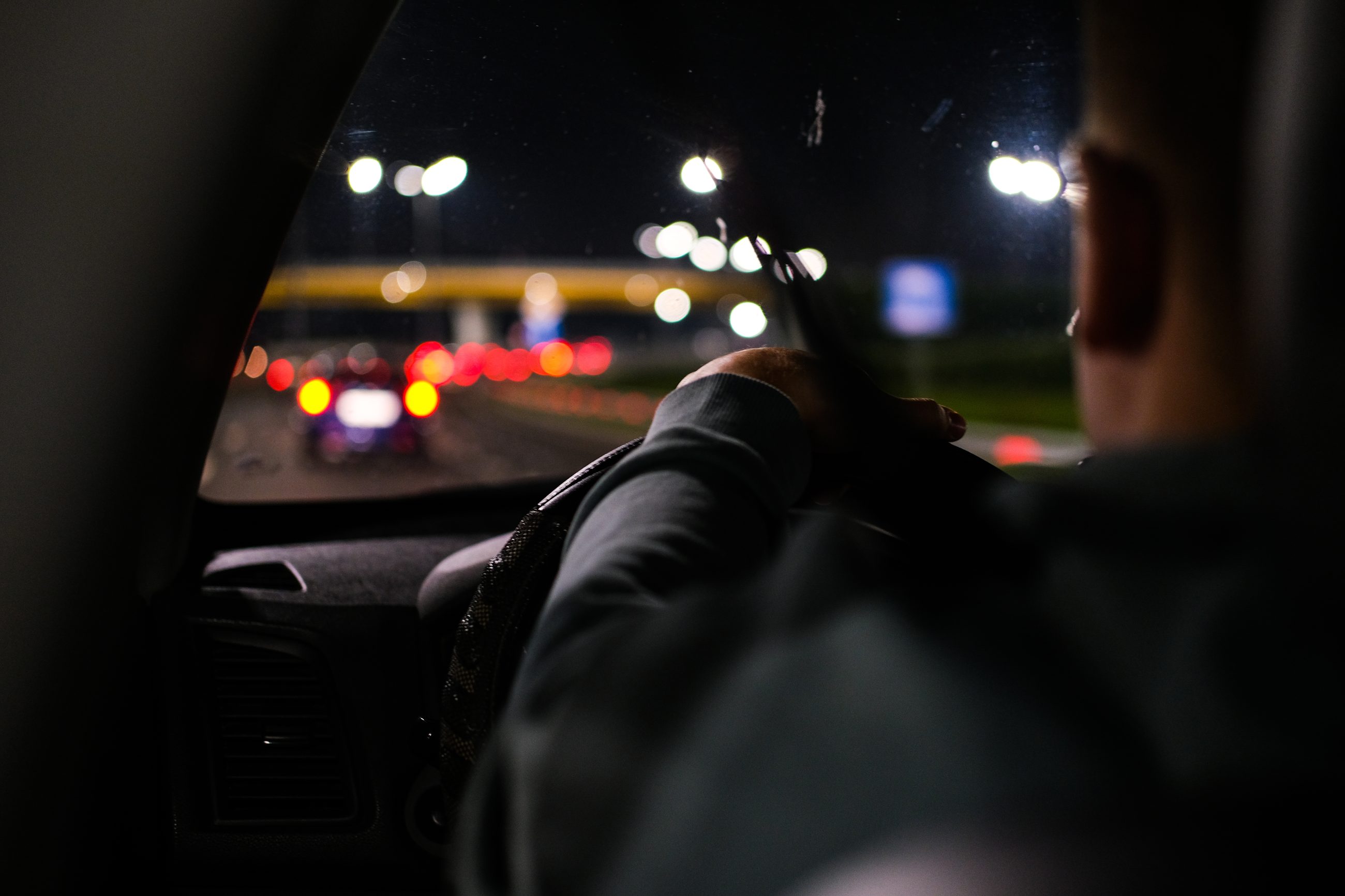 Autofahrer im nächtlichen Stadtverkehr aus der Rückansicht, Sinnbild für schnelle Urteile und den fundamentalen Attributionsfehler