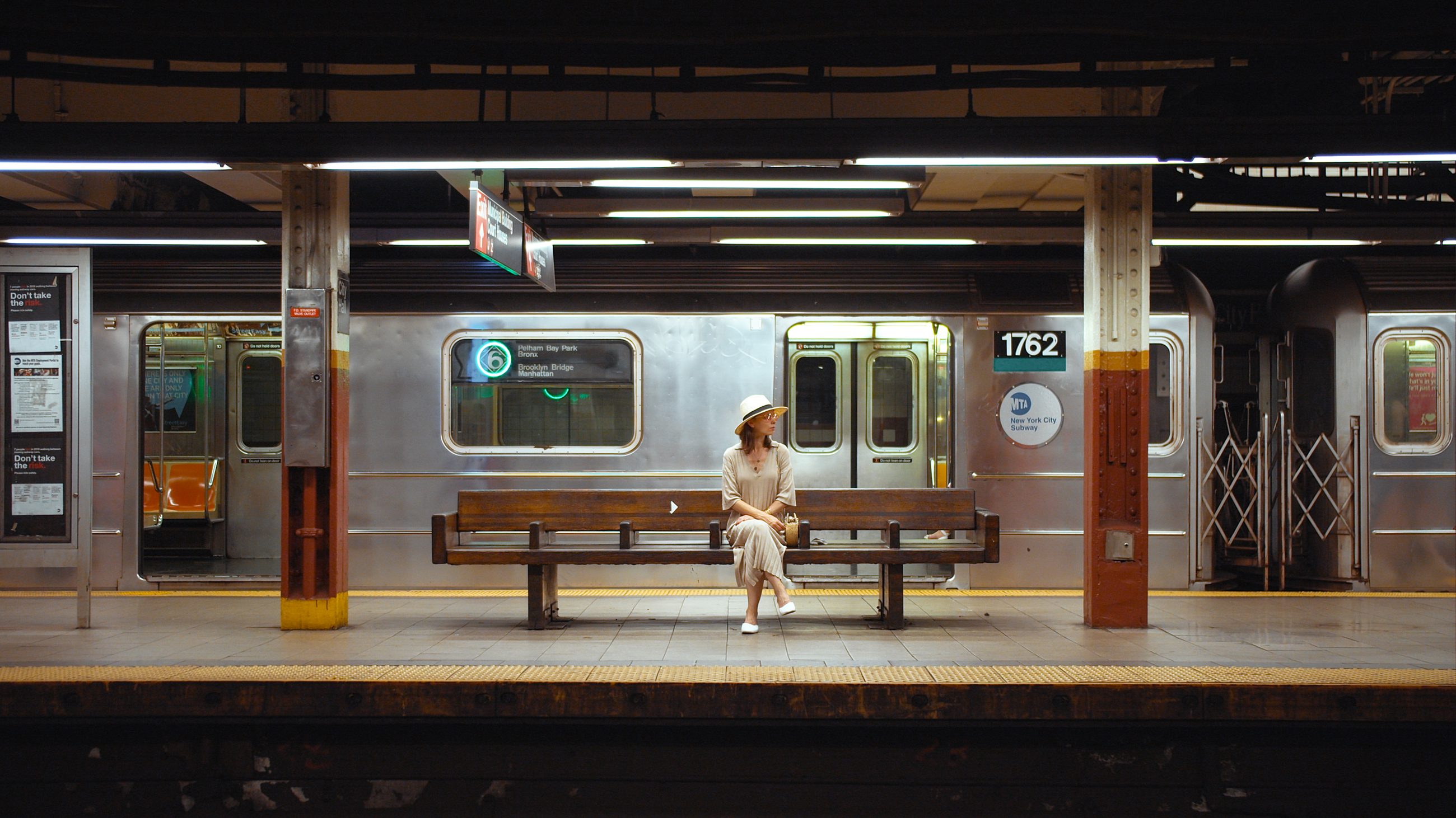 Wartende Frau allein auf der Bank eines U-Bahnsteigs, Sinnbild für den Bystander-Effekt und das Zögern in der Menge