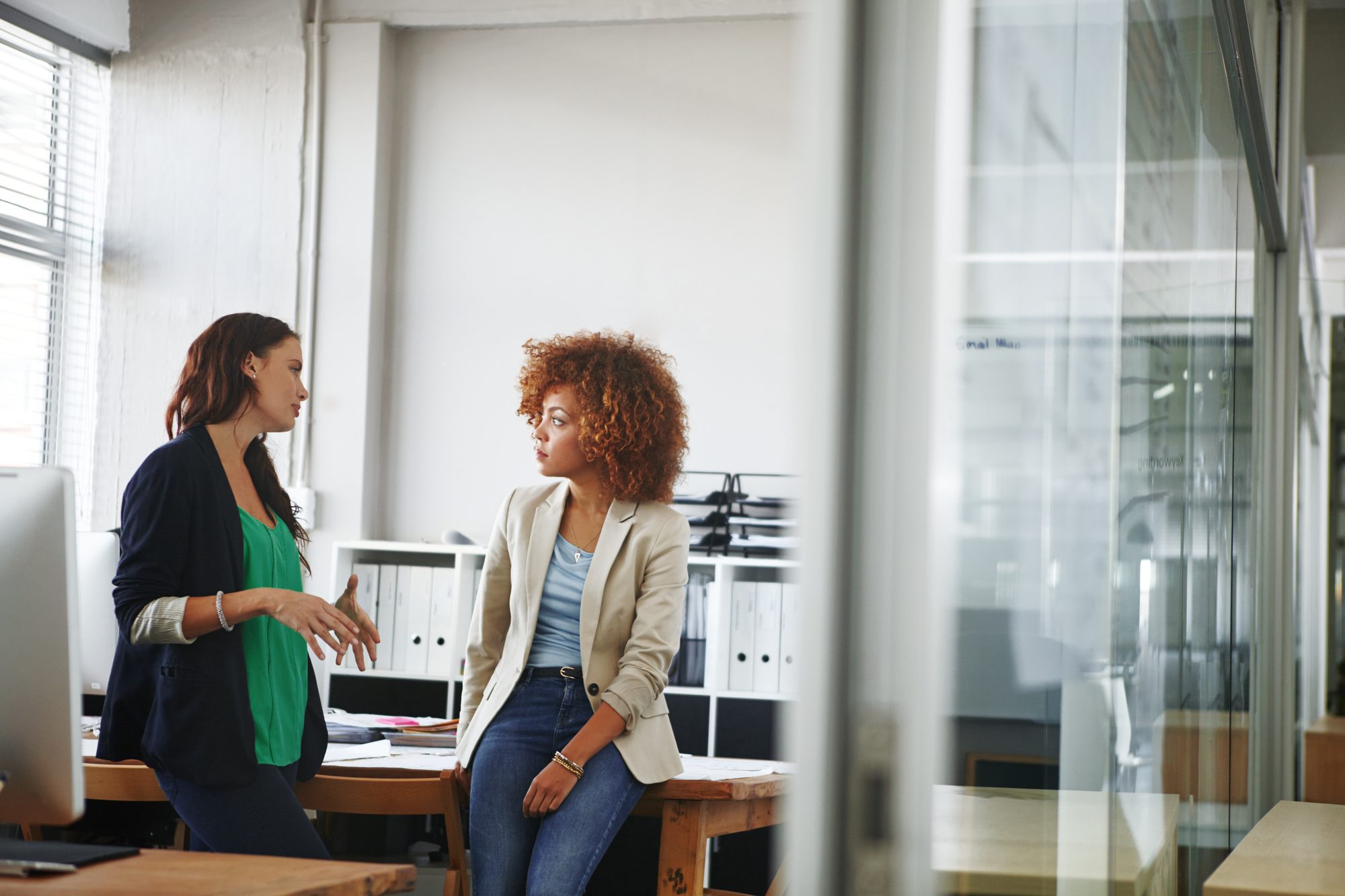 Zwei Frauen im konzentrierten Arbeitsgespräch am Schreibtisch im Büro, Sinnbild für kommunizierte Erwartungen zwischen Führungskraft und Mitarbeiterin