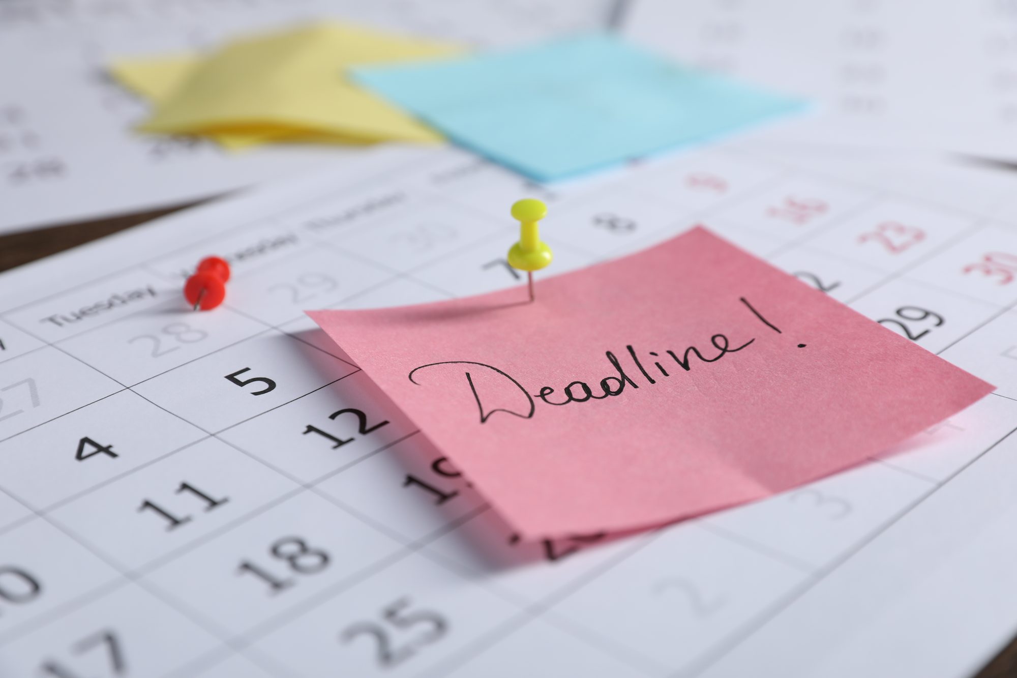 Kalenderblatt mit angepinnter Deadline-Notiz, Sinnbild für Zeitpläne, die im Planungsfehlschluss systematisch zu optimistisch angesetzt werden