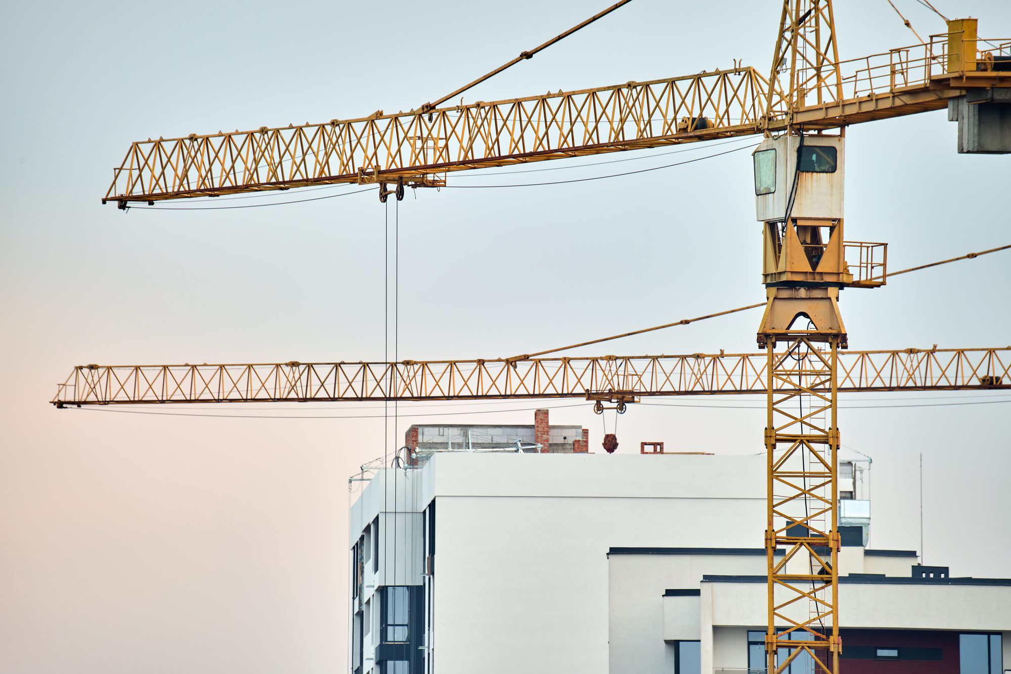 Baukran ragt über einen unfertigen Gebäudekomplex, Sinnbild für Großprojekte, die länger dauern und mehr kosten als geplant