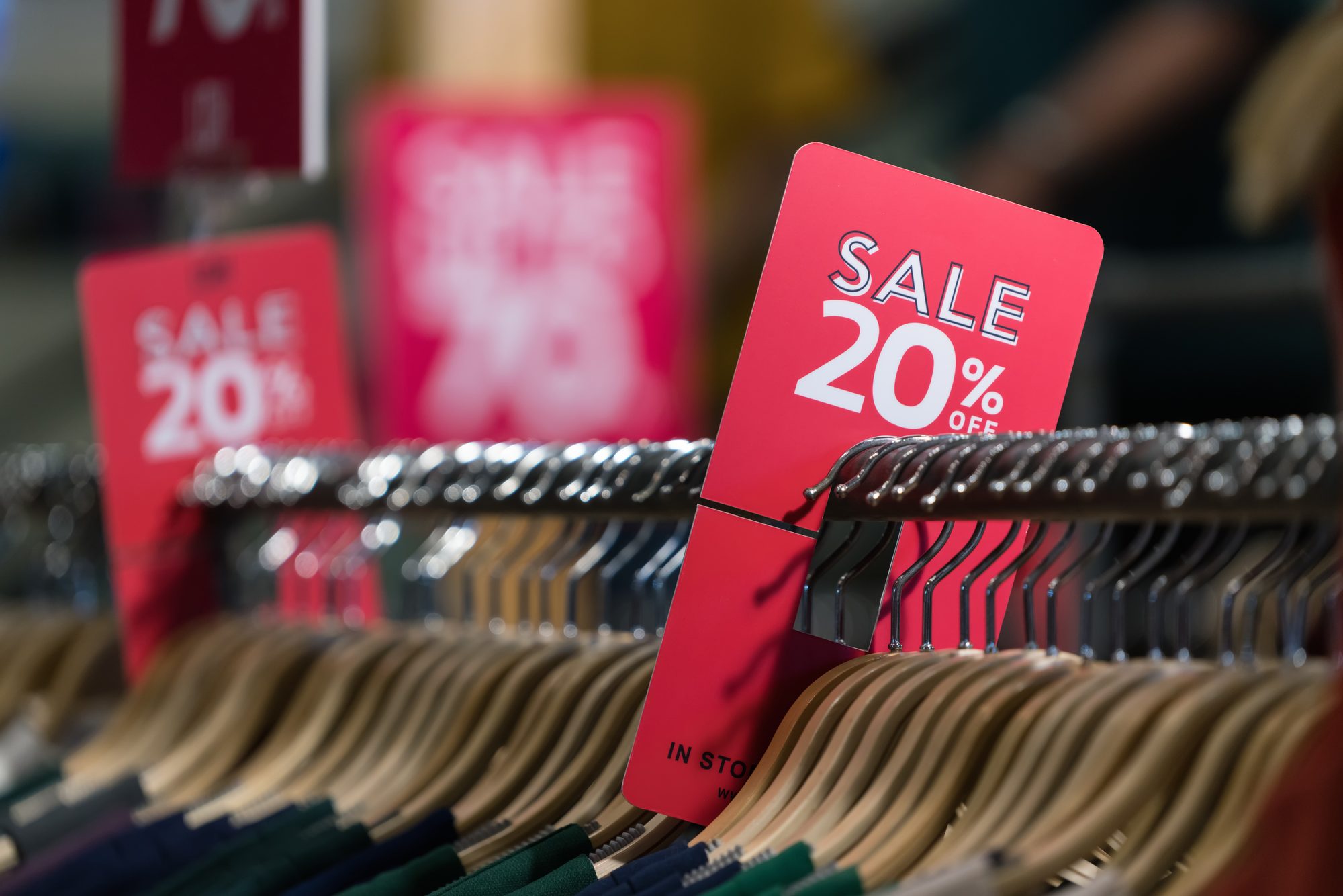 Rote Sale-Schilder mit 20 Prozent Rabatt an einer Kleiderstange, Sinnbild für durchgestrichene Preise als klassische Preisanker im Handel