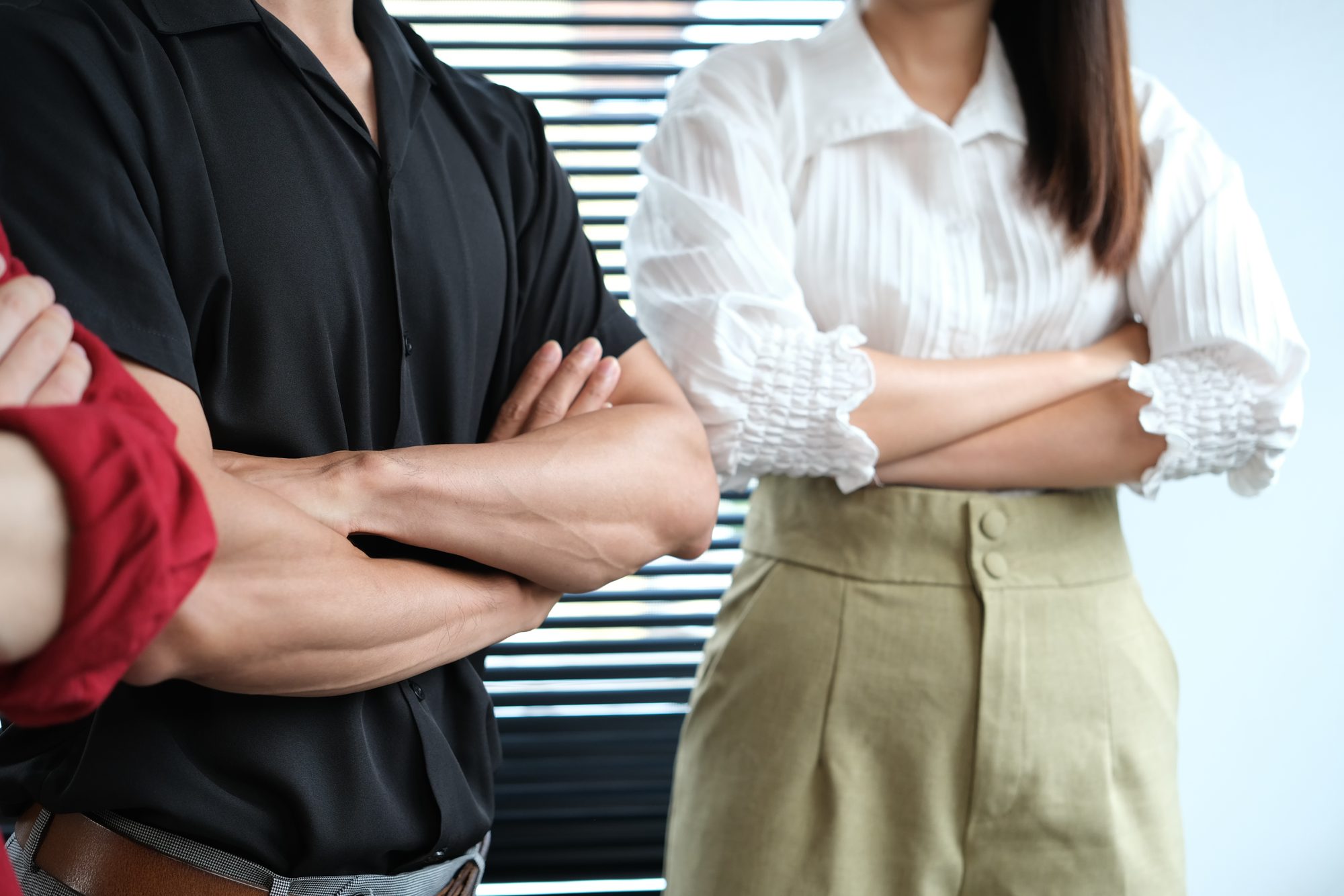 Kollegen stehen mit verschränkten Armen im Büro, Sinnbild für inneren Widerstand, wenn Menschen sich in ihrer Freiheit eingeschränkt fühlen