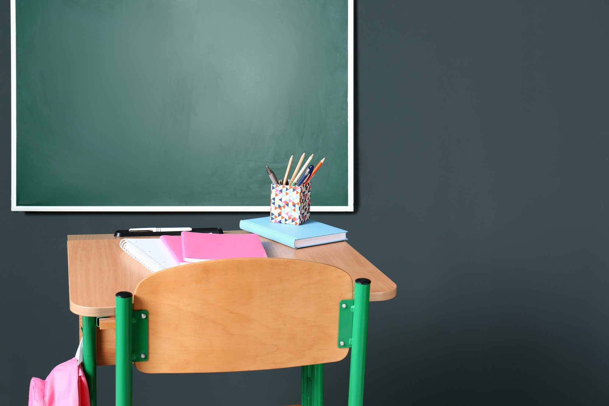 Schulbank vor grüner Tafel in einem leeren Klassenzimmer, Sinnbild für die großen Schulstudien zur Wirkung von Mindset-Interventionen