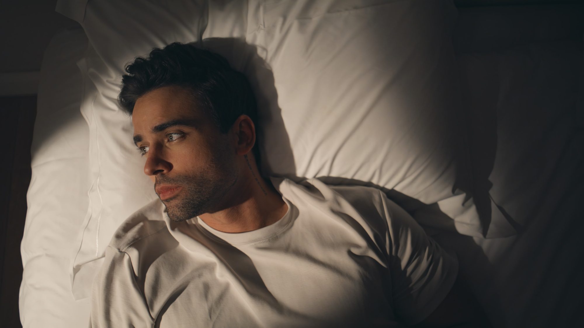 Mann liegt nachts wach im Bett und starrt an die Decke, Sinnbild für den Weißen-Bär-Effekt, bei dem unterdrückte Gedanken zurückkehren