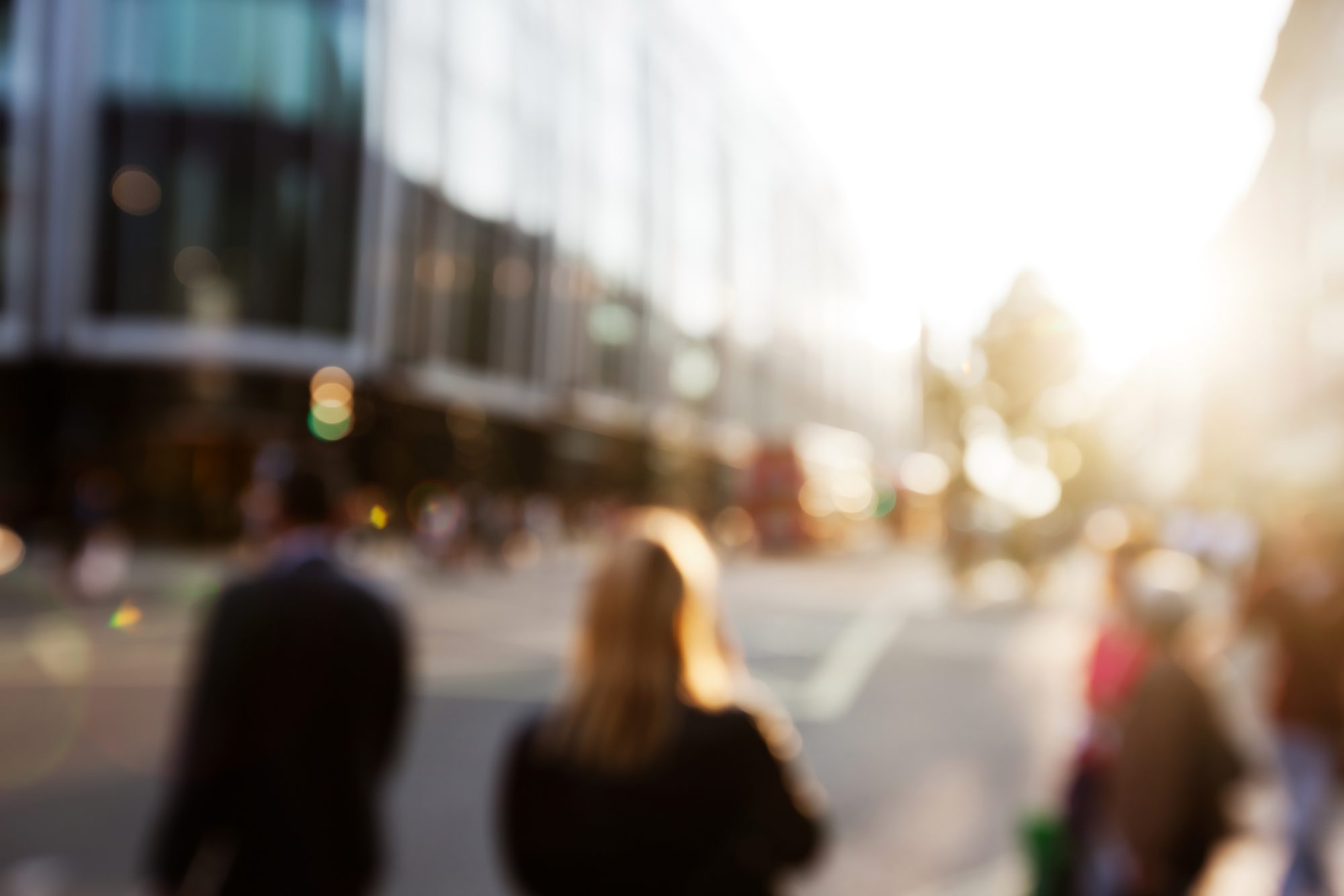 Unscharfe Menschen auf einer sonnigen Stadtstraße am Morgen, Sinnbild für die vielen wiederholten Begegnungen, aus denen der Effekt der bloßen Darbietung Sympathie macht